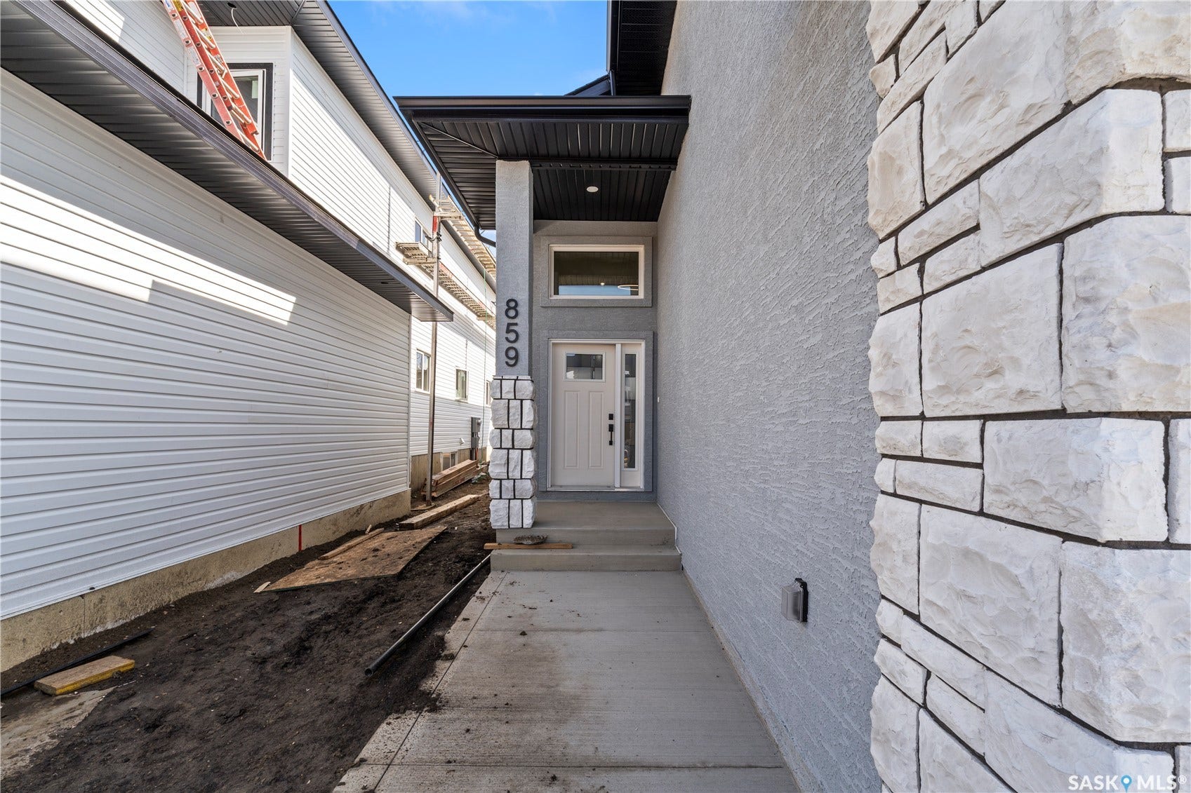 Stucco exterior with stone accent column, concrete pathway, and covered entry