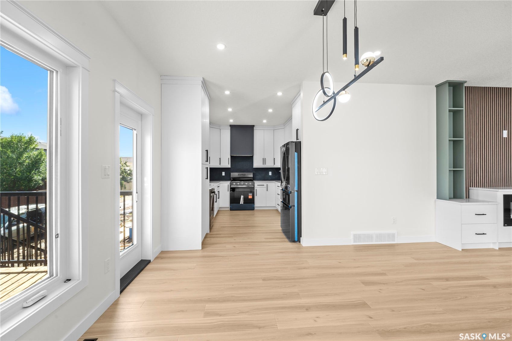 Open-concept living space with wood-finish flooring, recessed lighting, and a contemporary linear chandelier
