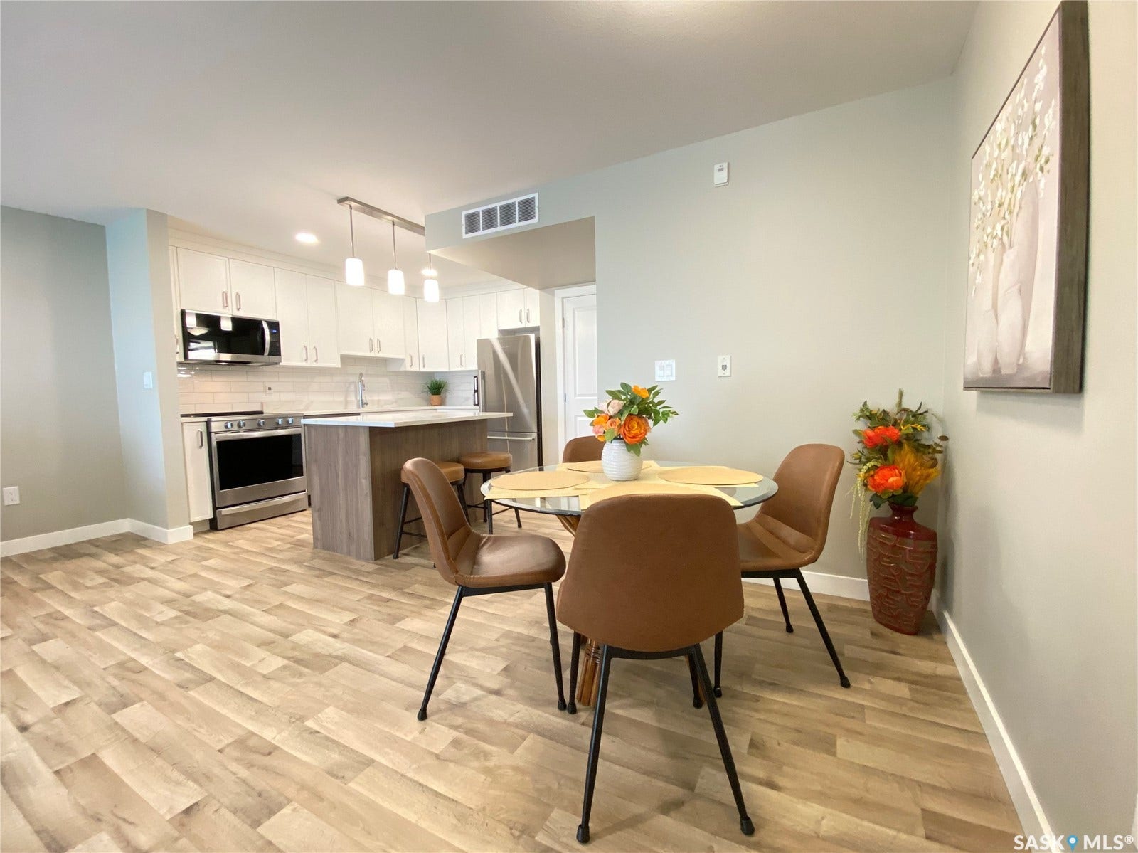 Modern kitchen featuring white cabinetry, stainless steel appliances, and a central island with bar seating