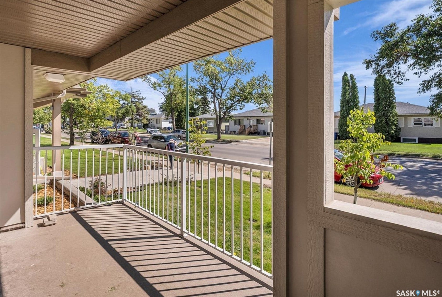 Covered concrete porch with white railing