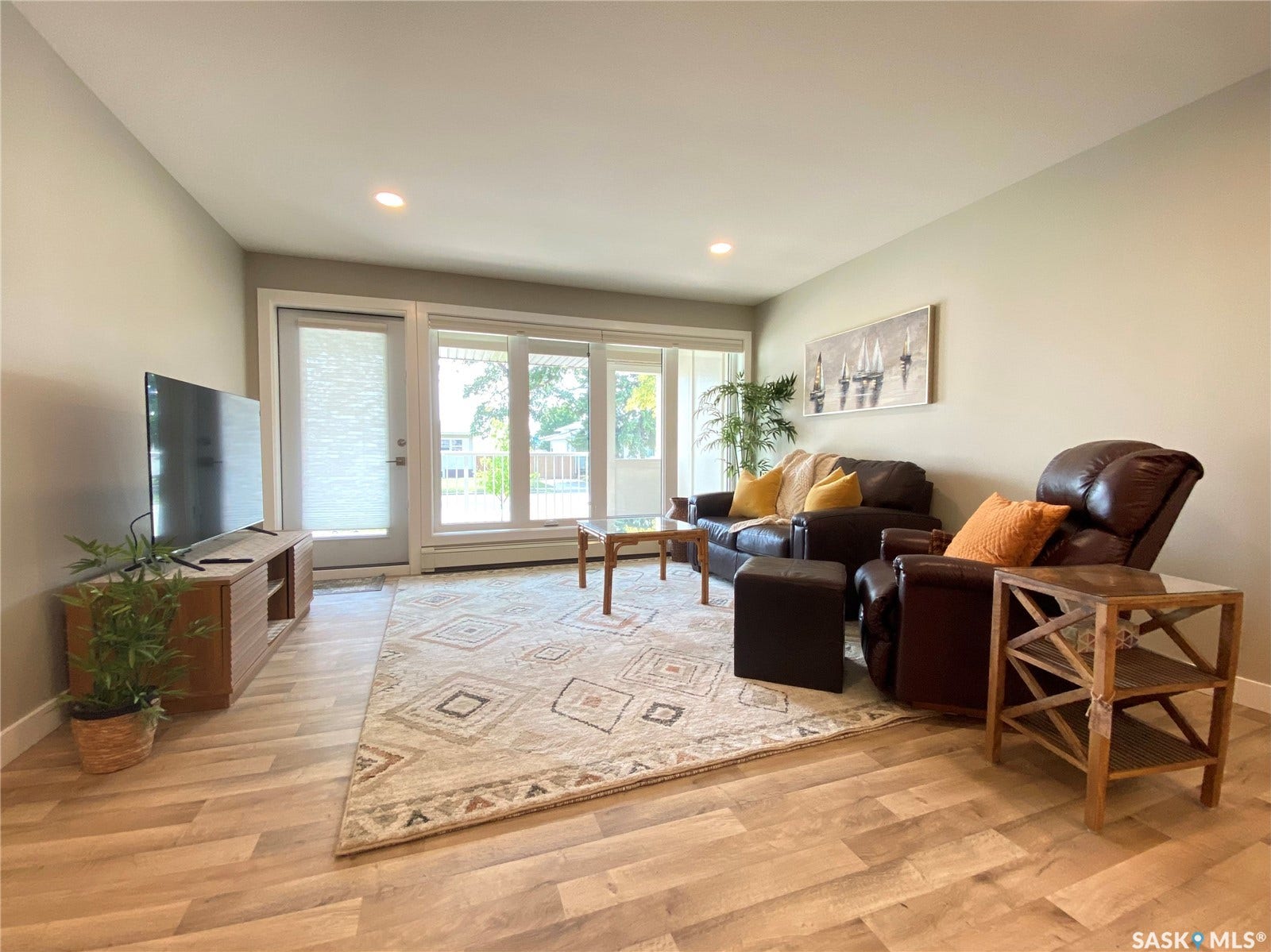 Recessed ceiling lighting, wood-finish flooring, light-toned wall paint, white trim, and a glass-paneled door