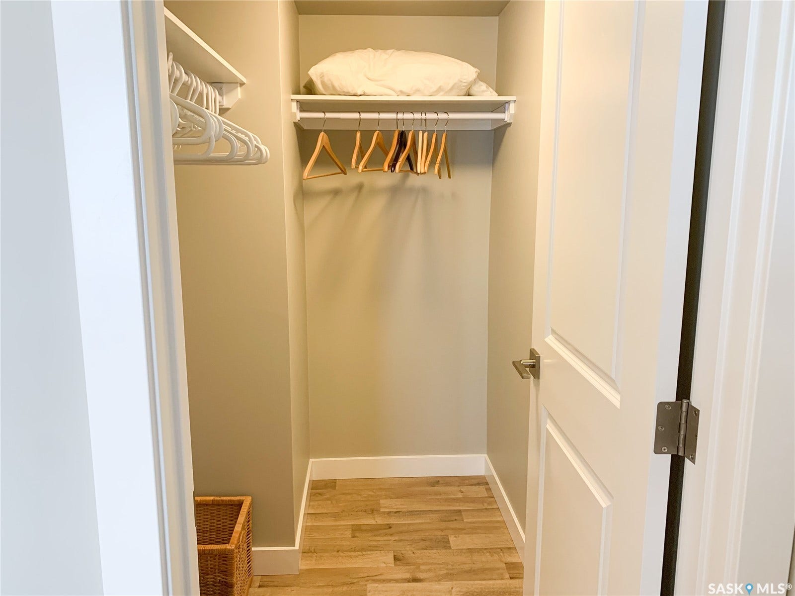 Closet with wood-finish flooring, built-in shelving, and a hanging rod