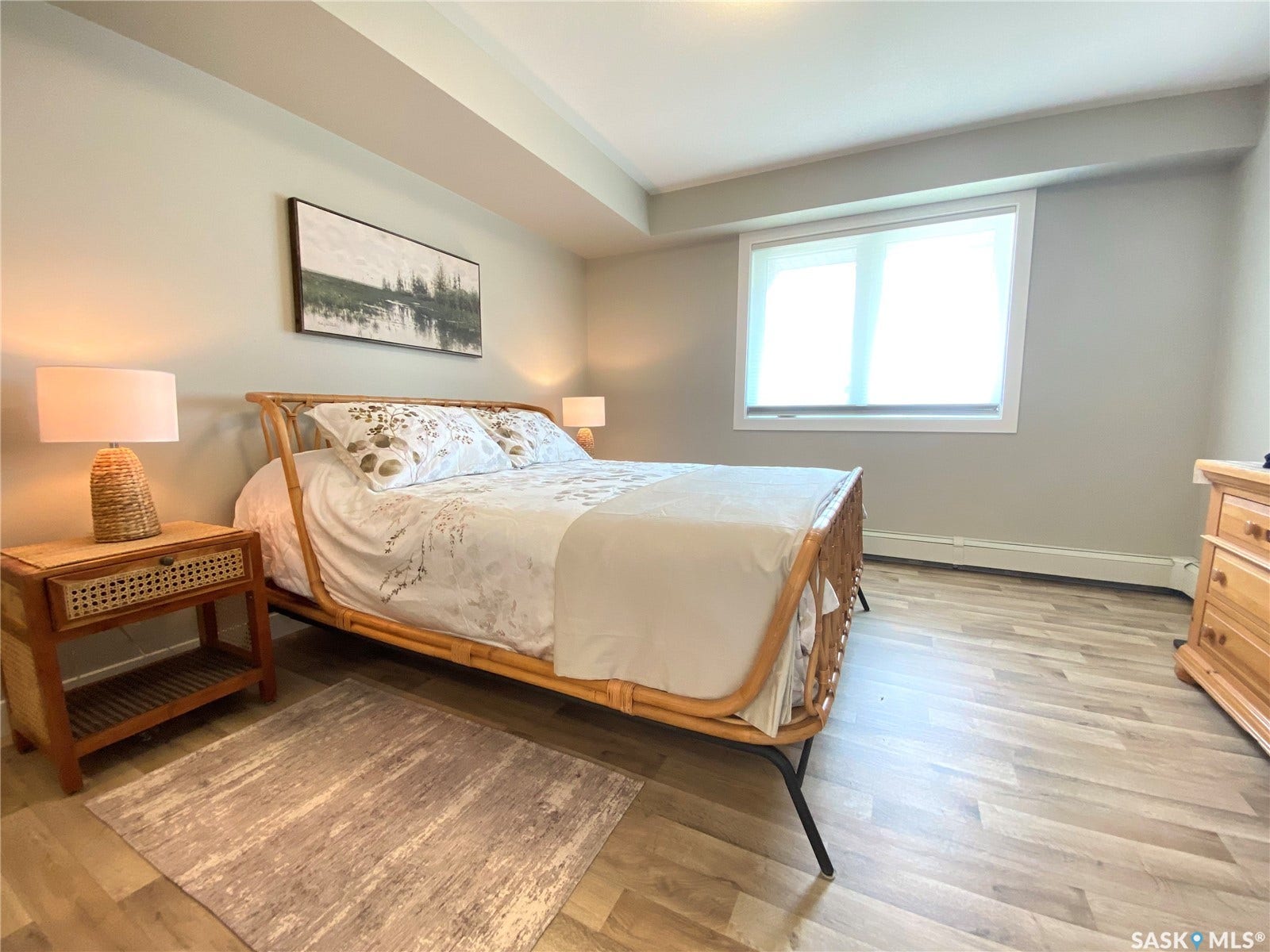 Light wood-finish flooring, a window with roller shade, and light-toned wall paint
