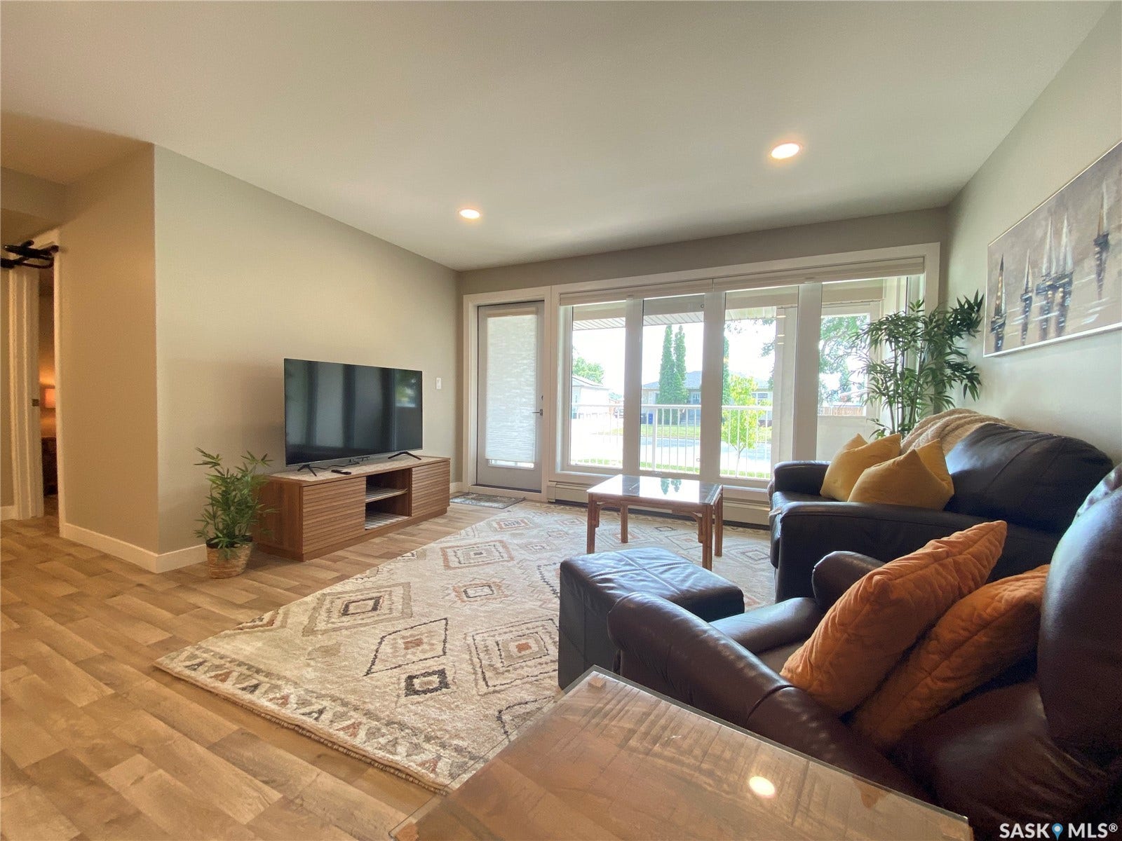 Recessed lighting, wood-finish flooring, and a large window with an exterior door