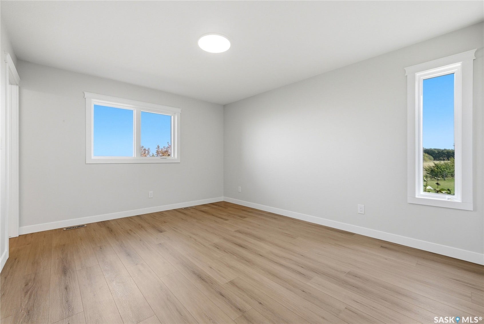 Wood-finish flooring, white trim, recessed ceiling light, and multiple windows