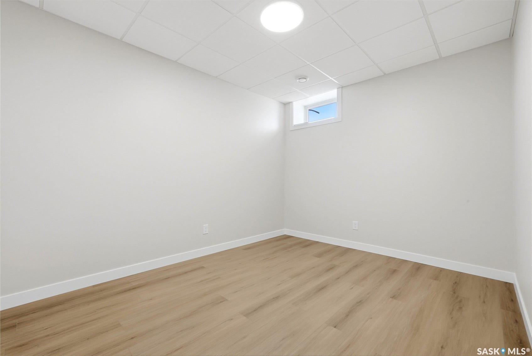 Wood-finish flooring, white trim, drop ceiling, recessed lighting, and a basement window