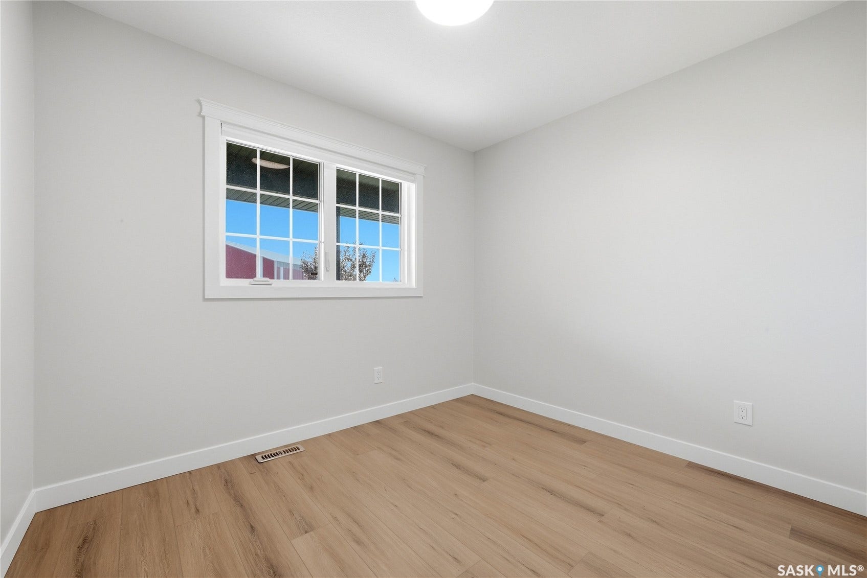 Light wood-finish flooring, white walls, white trim, and a multi-pane window
