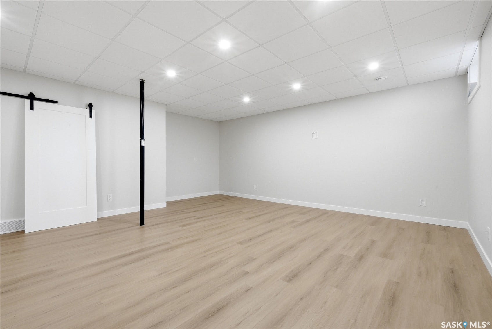 Recessed lighting, wood-finish flooring, white barn door, drop ceiling, and a high window