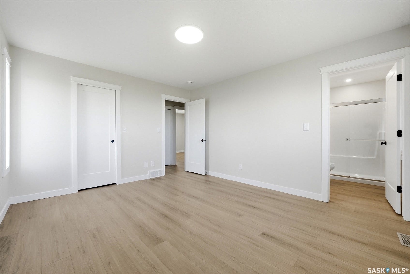 Recessed ceiling light, wood-finish flooring, white trim, white interior doors, and a bathroom with a tub/shower combination