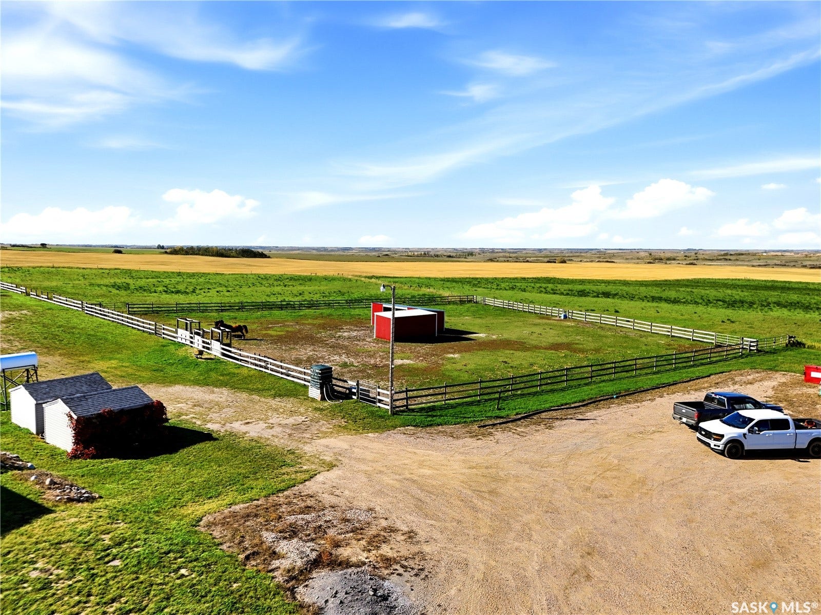 Expansive agricultural land featuring a fenced paddock, red barn, and outbuildings