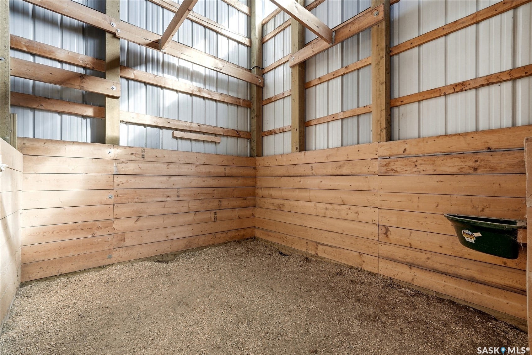 Interior stall featuring wood paneling, corrugated metal upper walls, and exposed wood beams