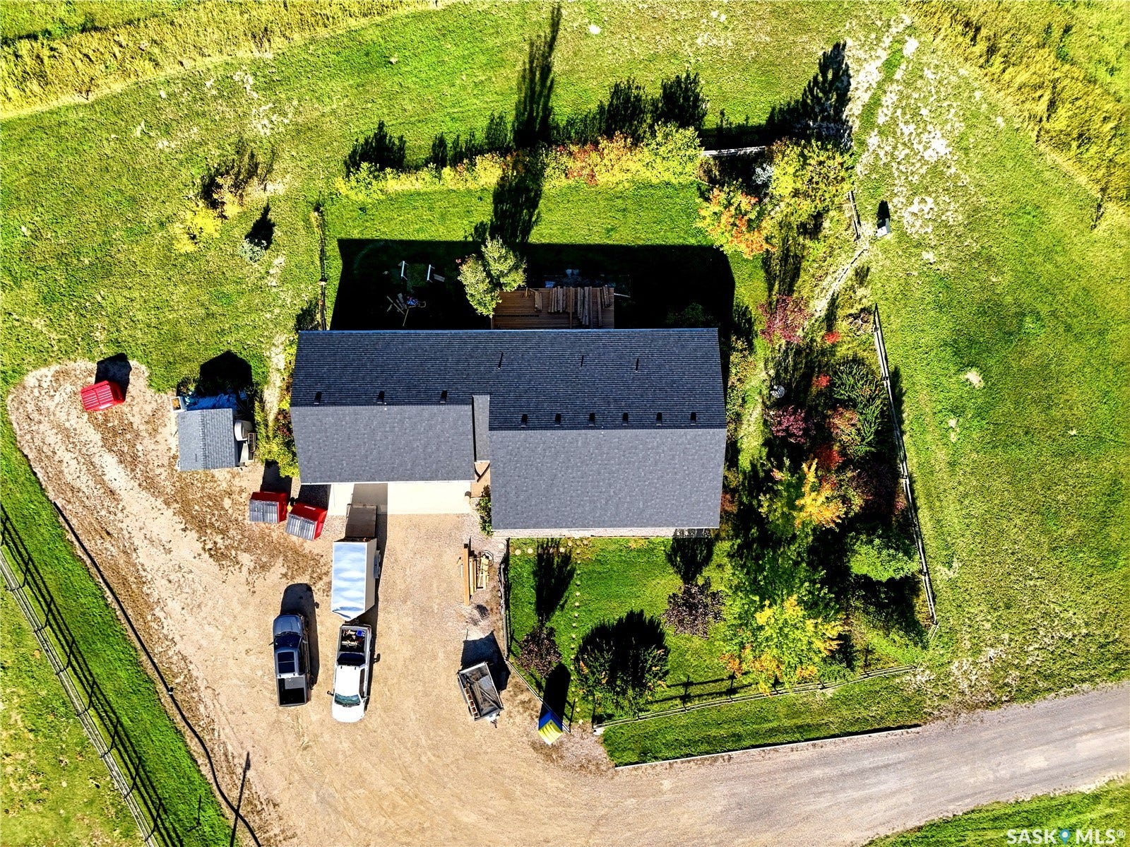 Expansive property with a dark shingle roof, established landscaping, and a gravel driveway