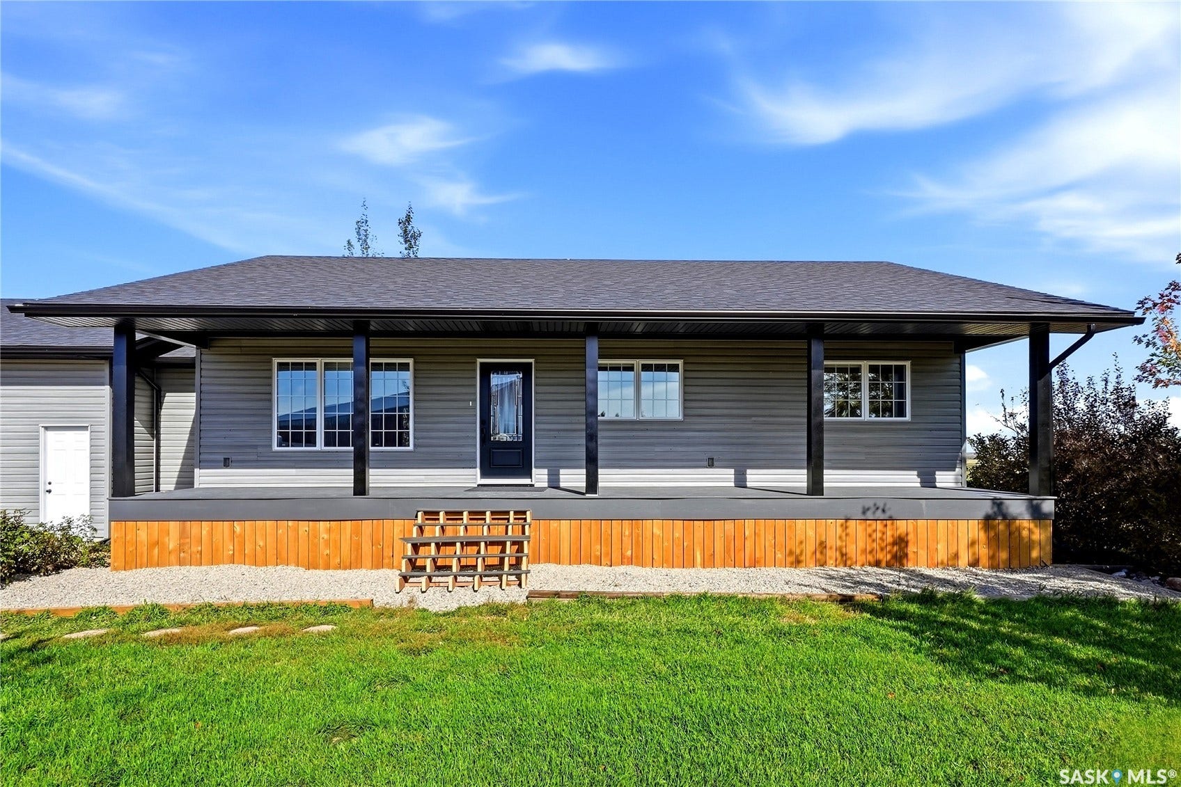 Front exterior featuring a covered porch with black support columns, grey siding, a dark roof, and a dark entry door
