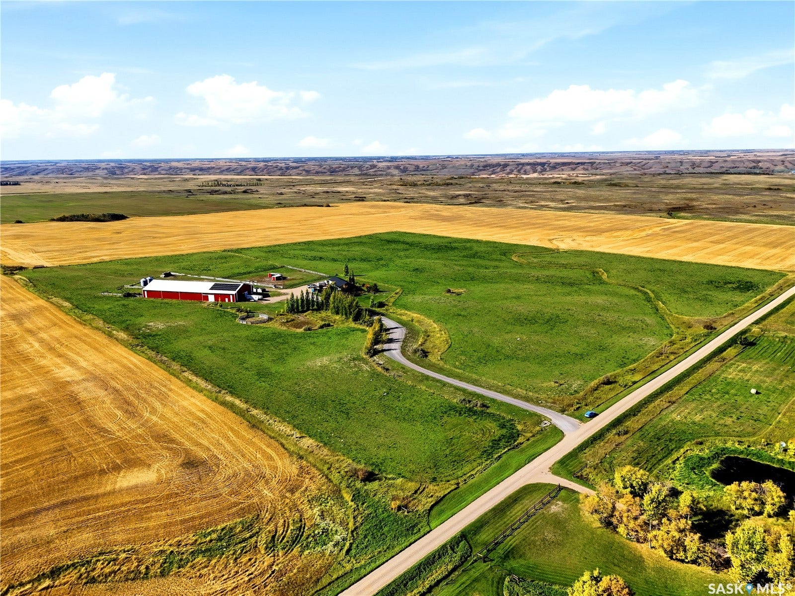 Expansive rural property featuring a red barn, verdant fields, and a winding driveway