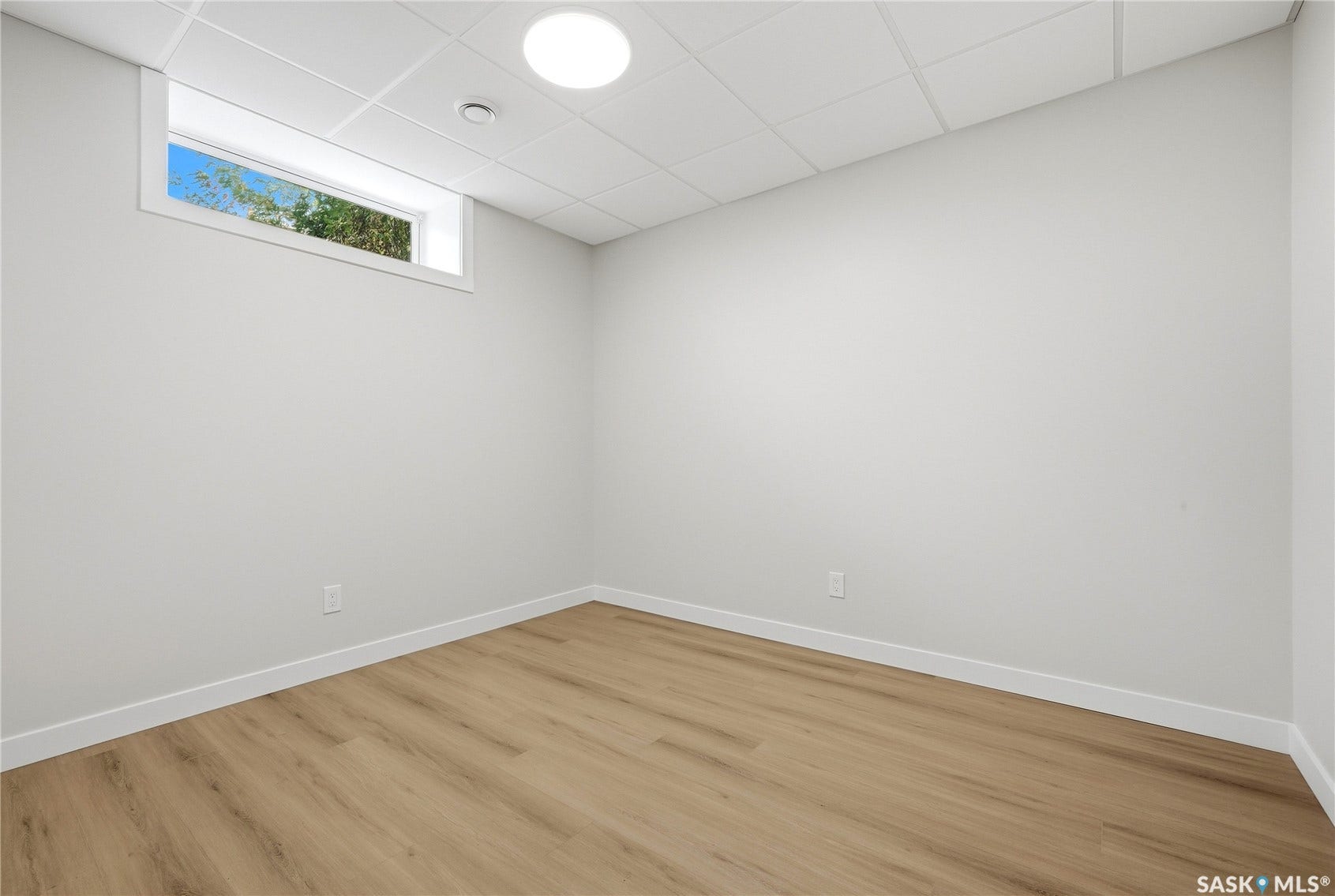 Recessed window, drop ceiling, wood-finish flooring, white walls, flush mount ceiling light