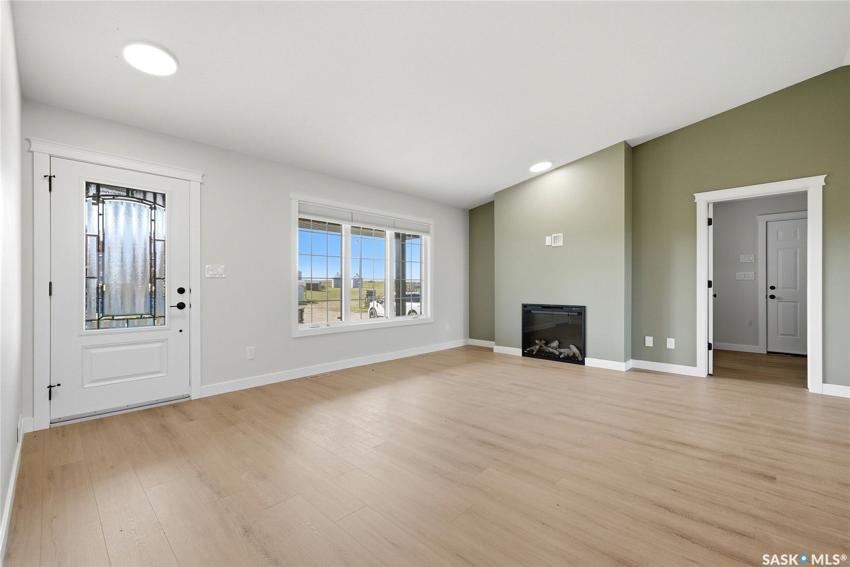 Light wood-finish flooring, vaulted ceilings, and a built-in electric fireplace