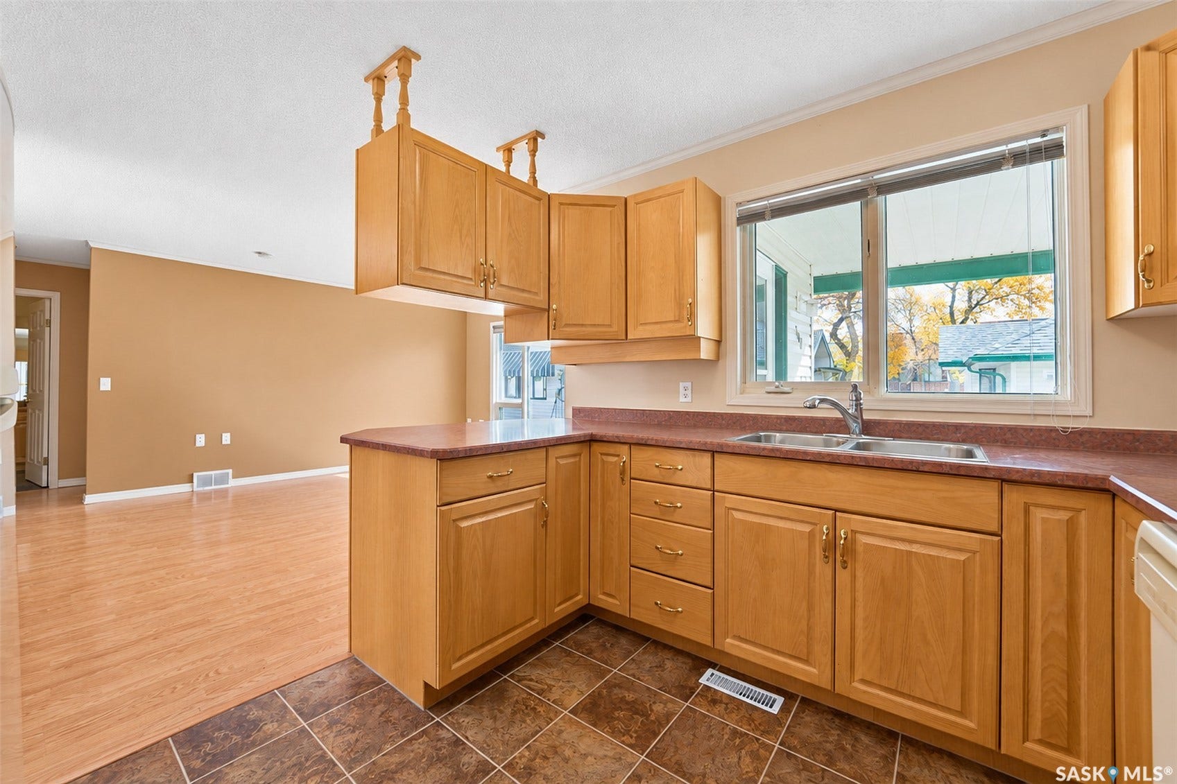 Kitchen with wood-finish cabinetry, a double basin sink, and a red-toned countertop