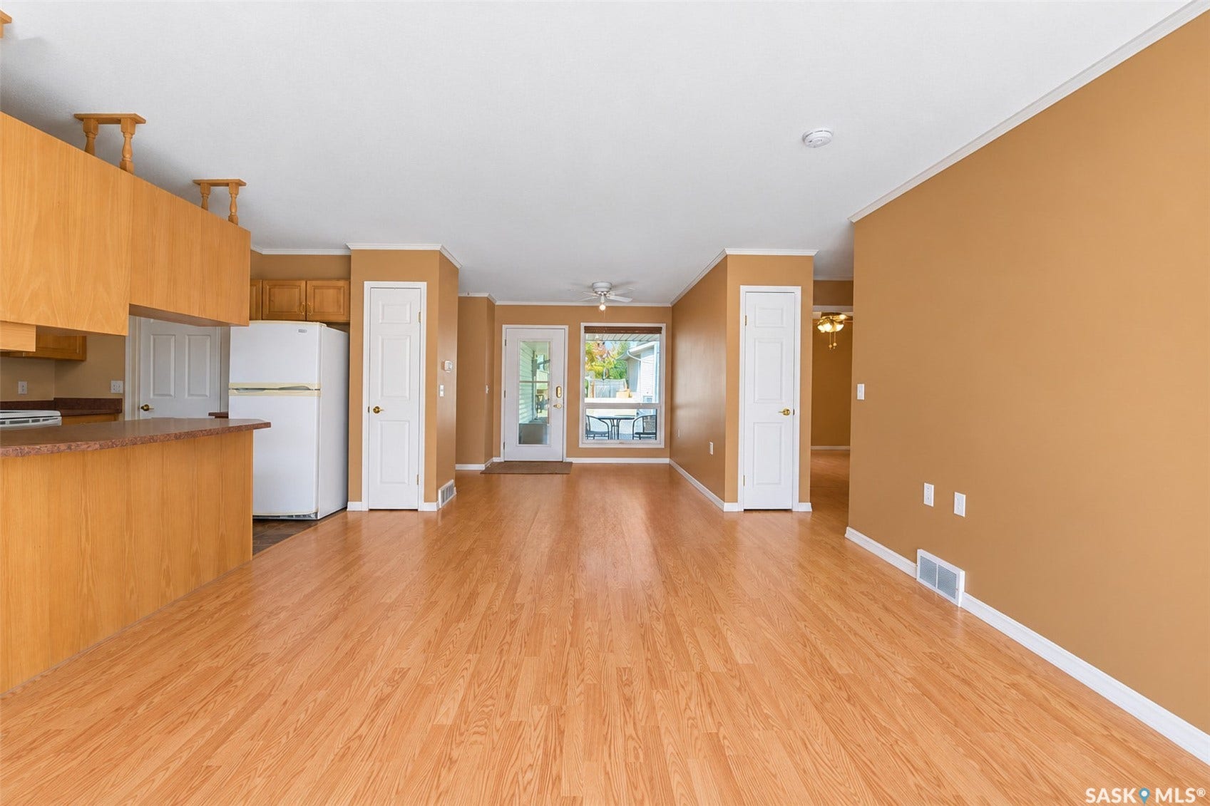 Expansive living area with wood-finish flooring, light-colored walls, and a ceiling fan