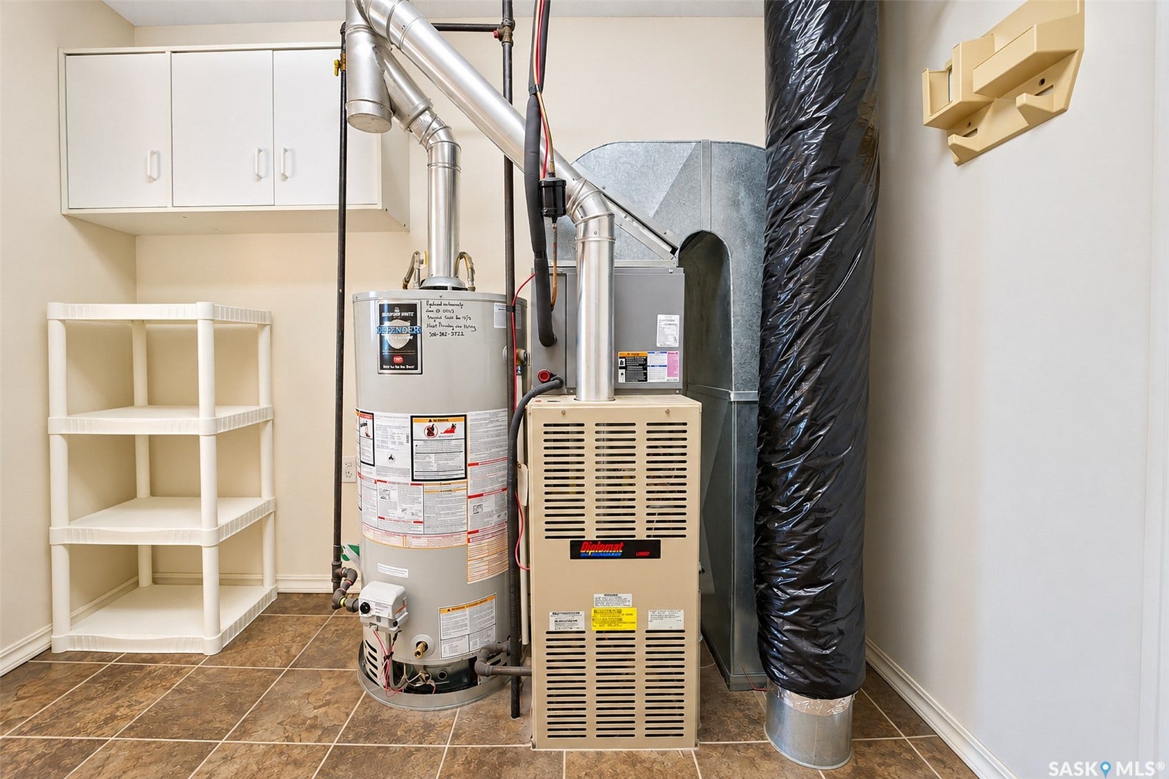 Tile flooring, built-in upper cabinetry, and a water heater with an attached furnace