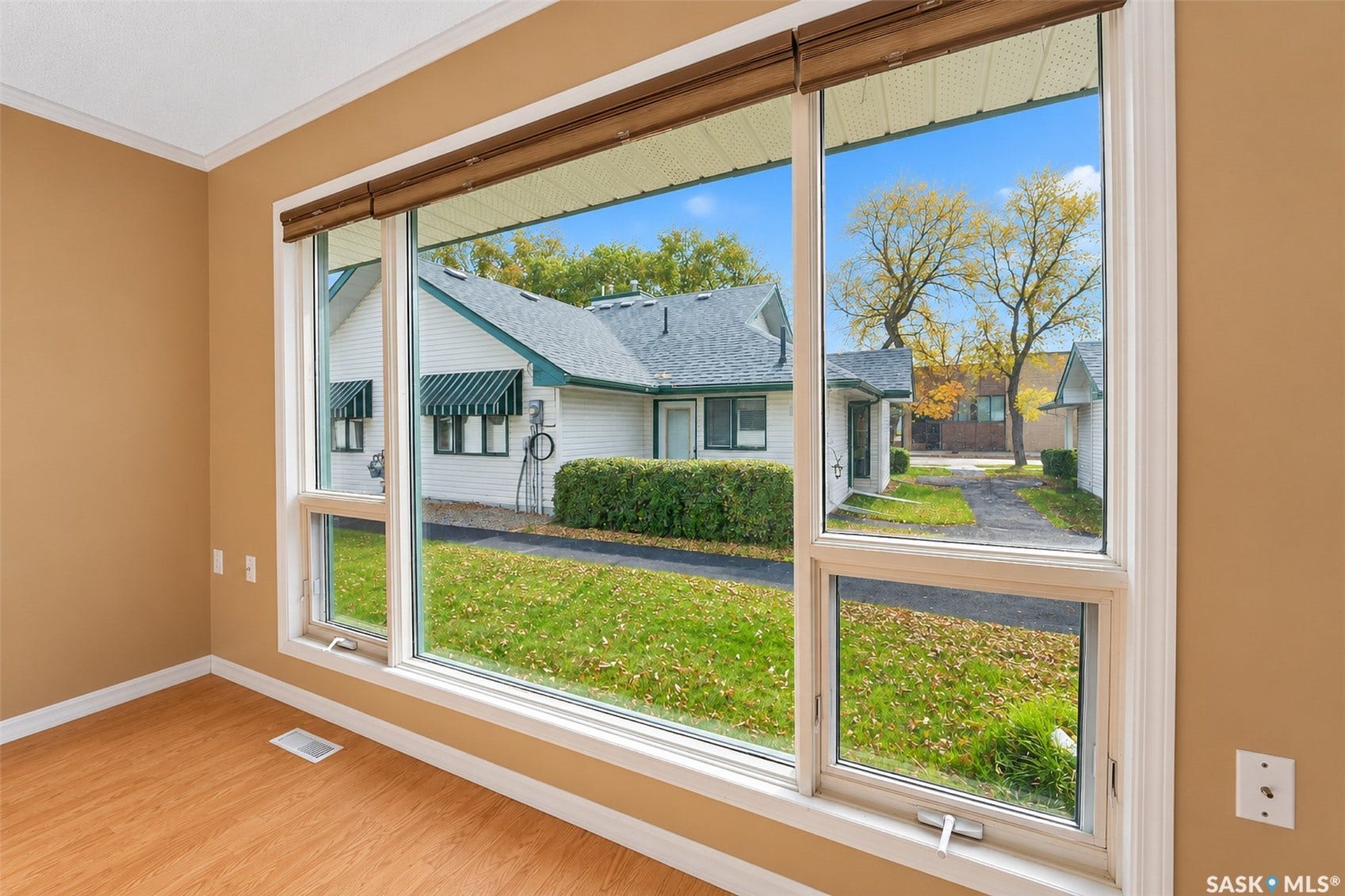 Expansive window unit with multiple panes and white trim, wood-finish flooring, and light-toned wall paint
