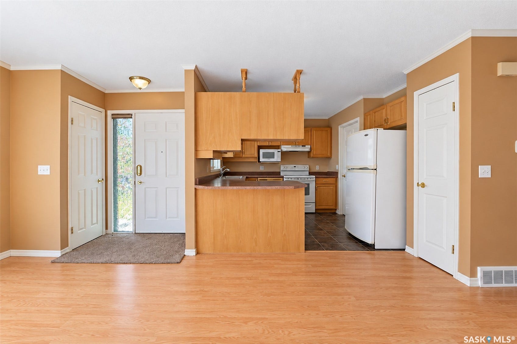 Wood-finish flooring throughout, kitchen with wood cabinetry, and a full suite of white appliances