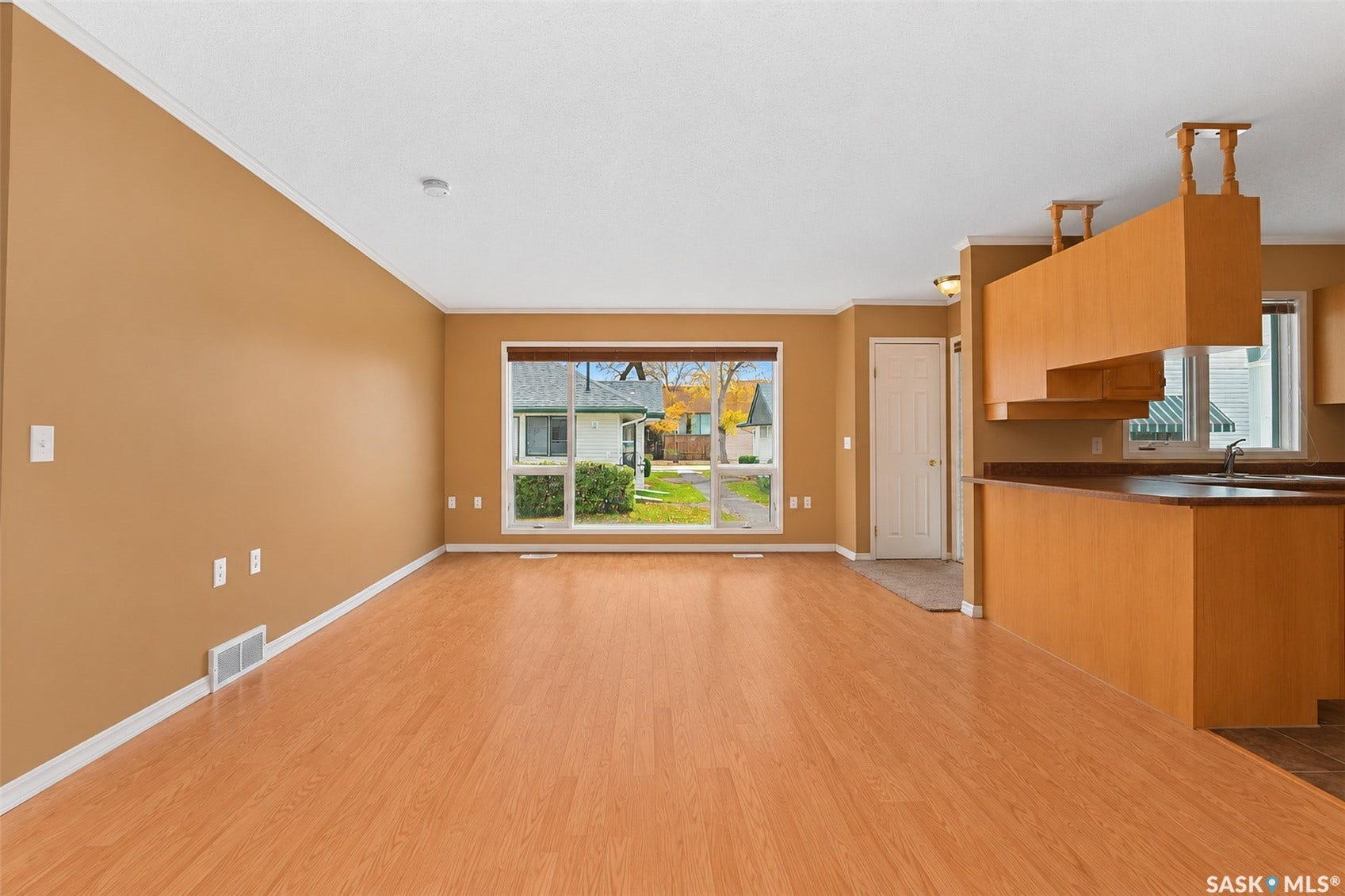 Expansive living area with wood-finish flooring, a large picture window, and a built-in breakfast bar with wood cabinetry