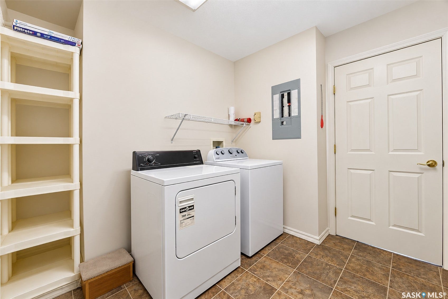 Laundry area featuring tiled flooring, built-in shelving, and a wall-mounted storage shelf