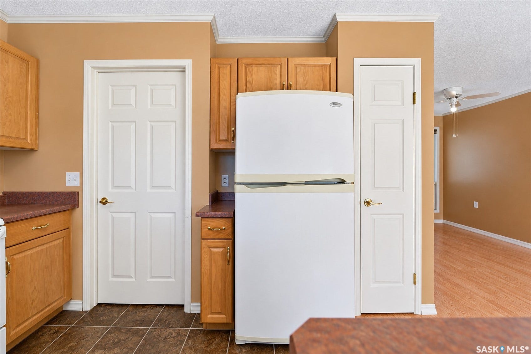 Kitchen area featuring wooden cabinetry, dark countertop surfaces, a built-in refrigerator, and tile flooring