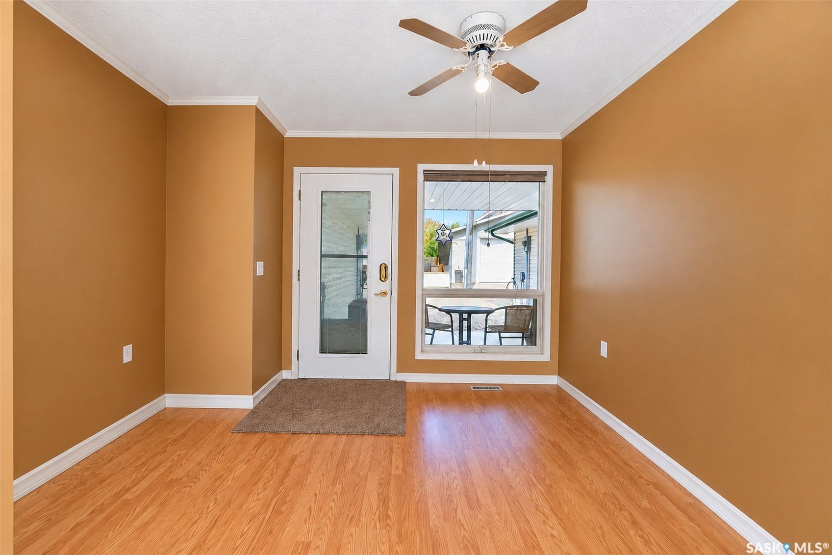 Wood-finish flooring, white trim, and a ceiling fan with integrated lighting