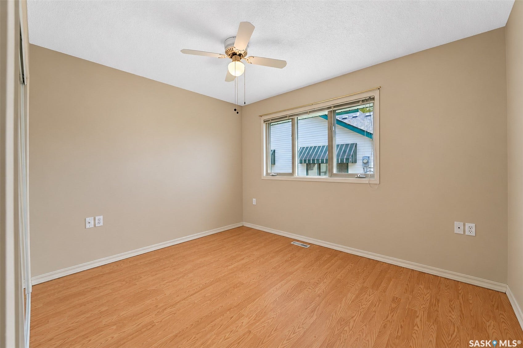 Wood-finish flooring, neutral wall tones, window with blind, ceiling fan with integrated lighting