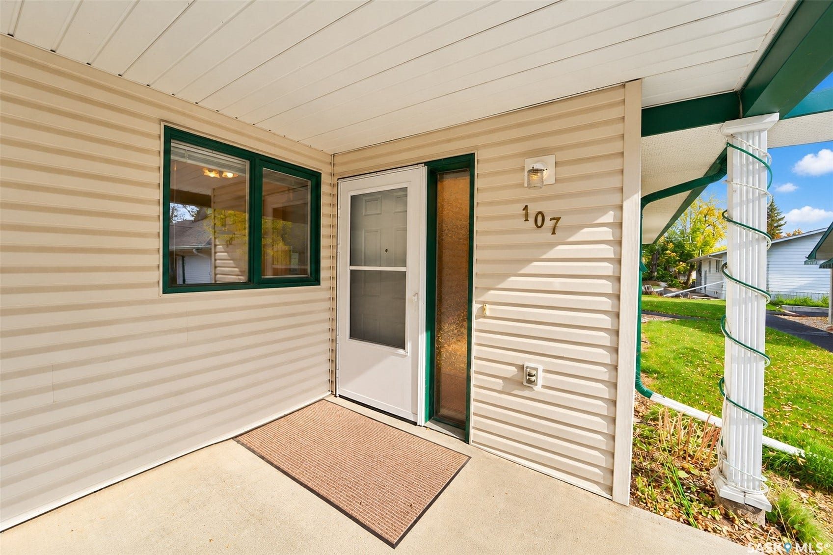 Entry with neutral-toned siding, white trim, and a green accent window frame
