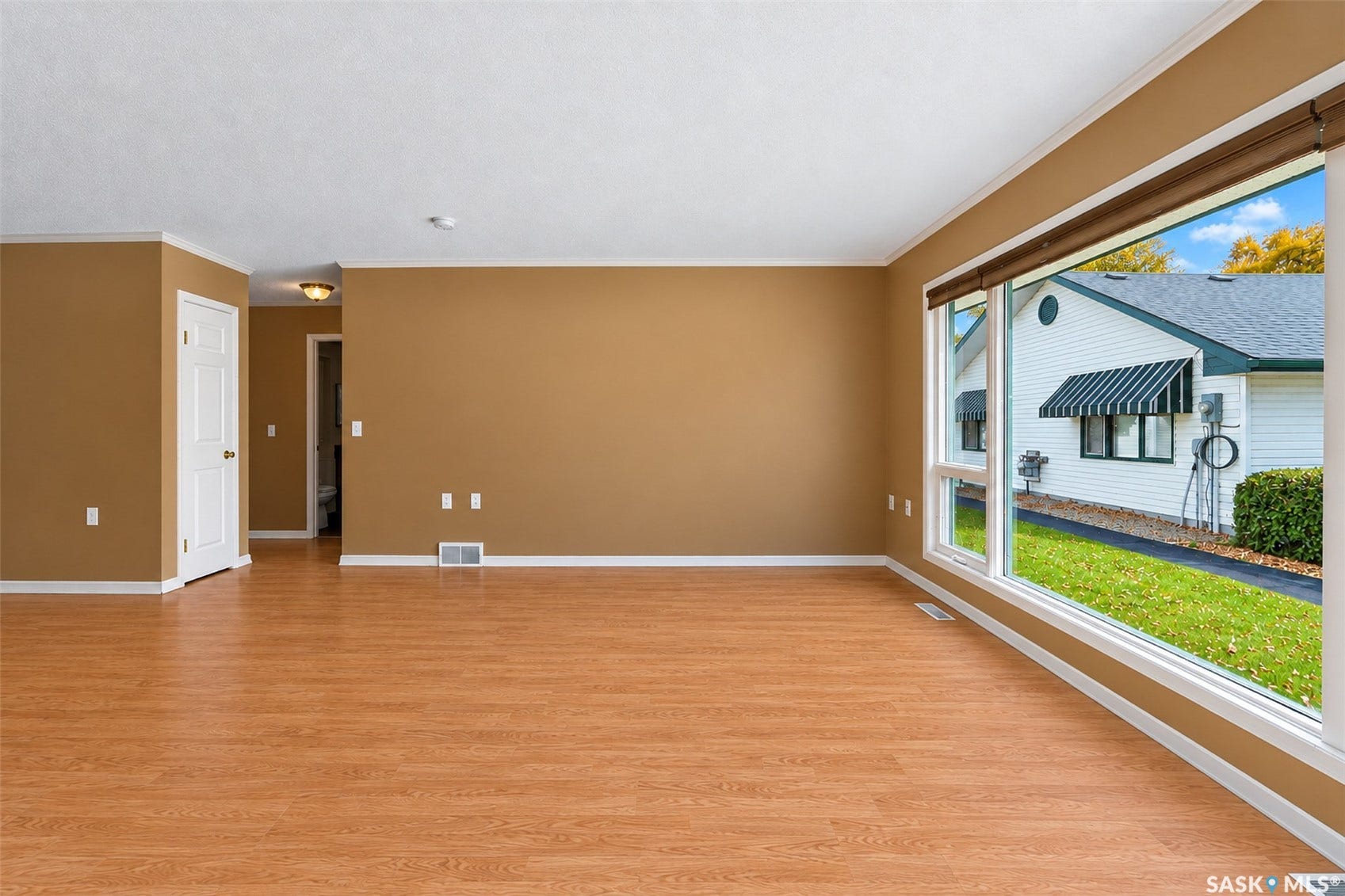 Spacious room featuring wood-finish flooring, a large picture window, and neutral wall tones