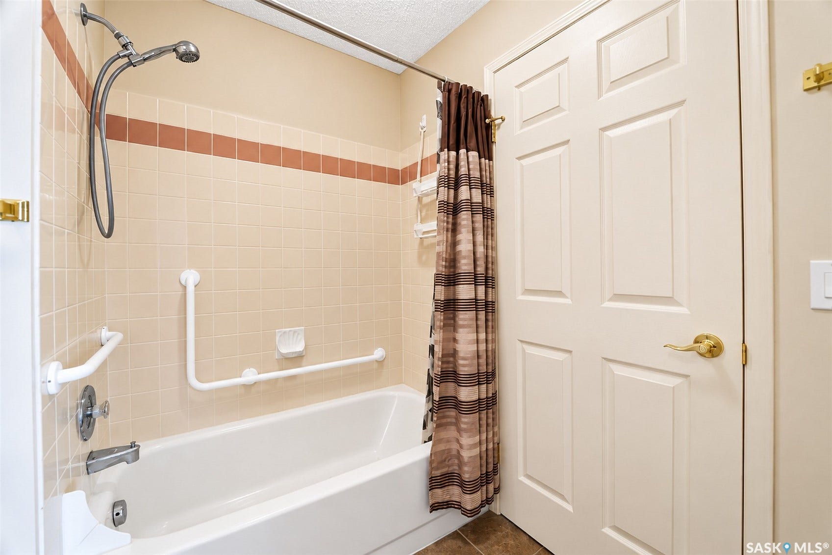 Bathtub with ceramic tile surround, integrated grab bars, and a handheld shower head