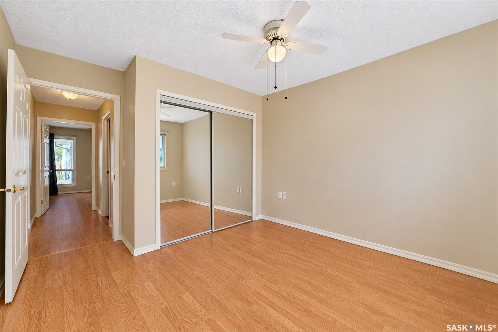 Wood-finish flooring throughout the space, featuring a ceiling fan with integrated lighting