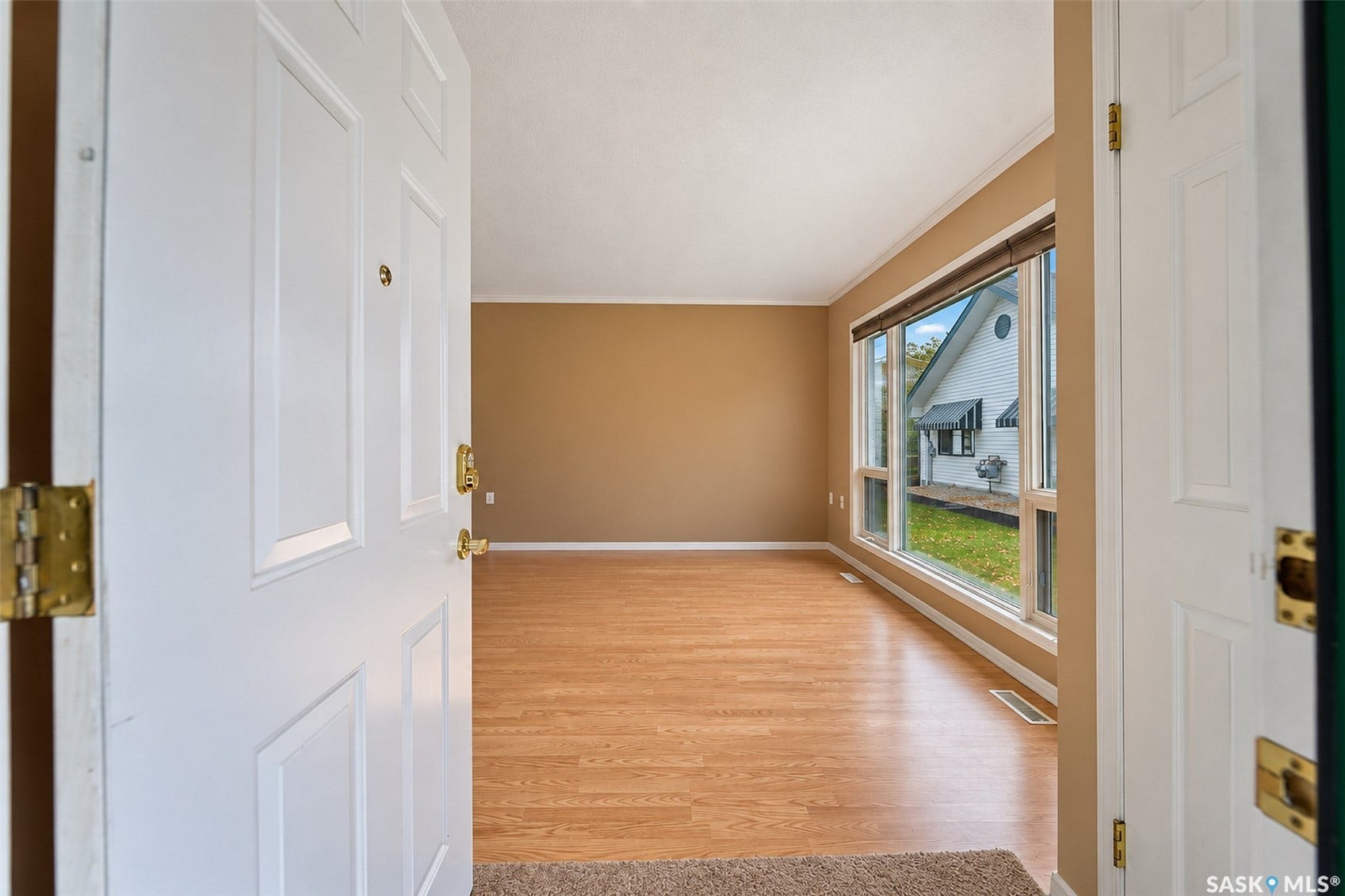 Wood-finish flooring with a neutral wall color, white trim, and a large picture window