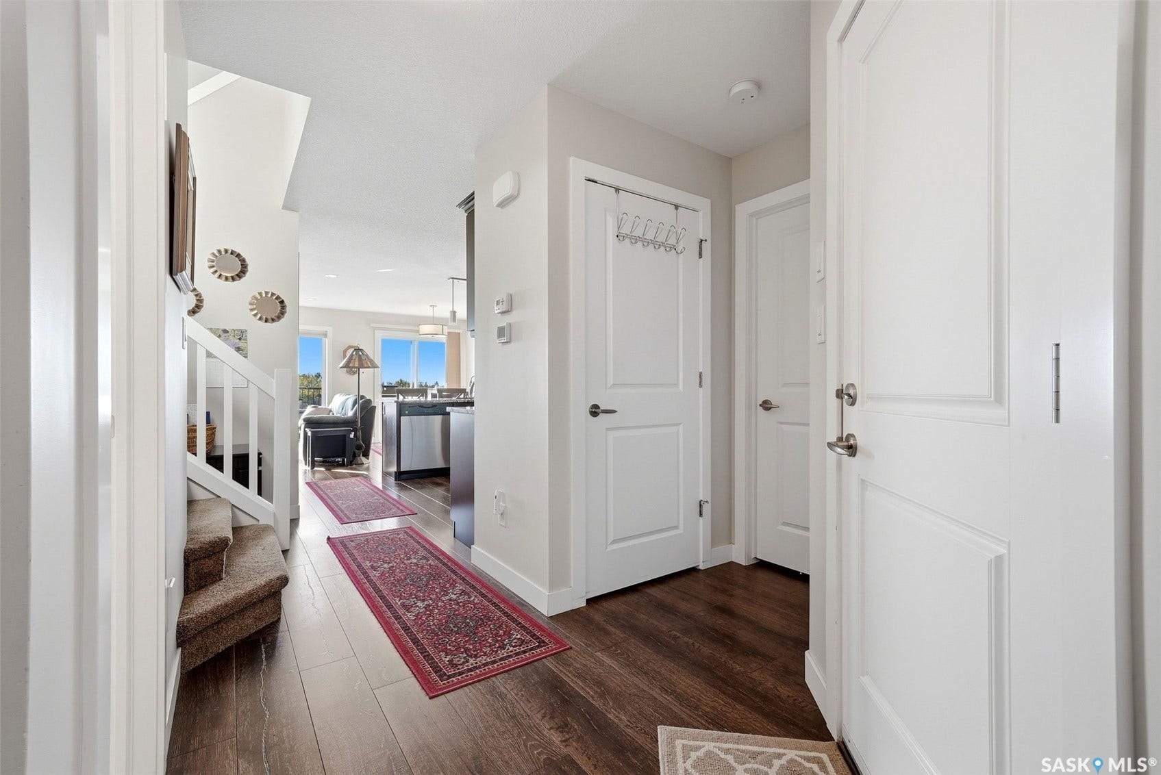 Wood-finish flooring throughout the entry, white paneled doors, and staircase with white railing