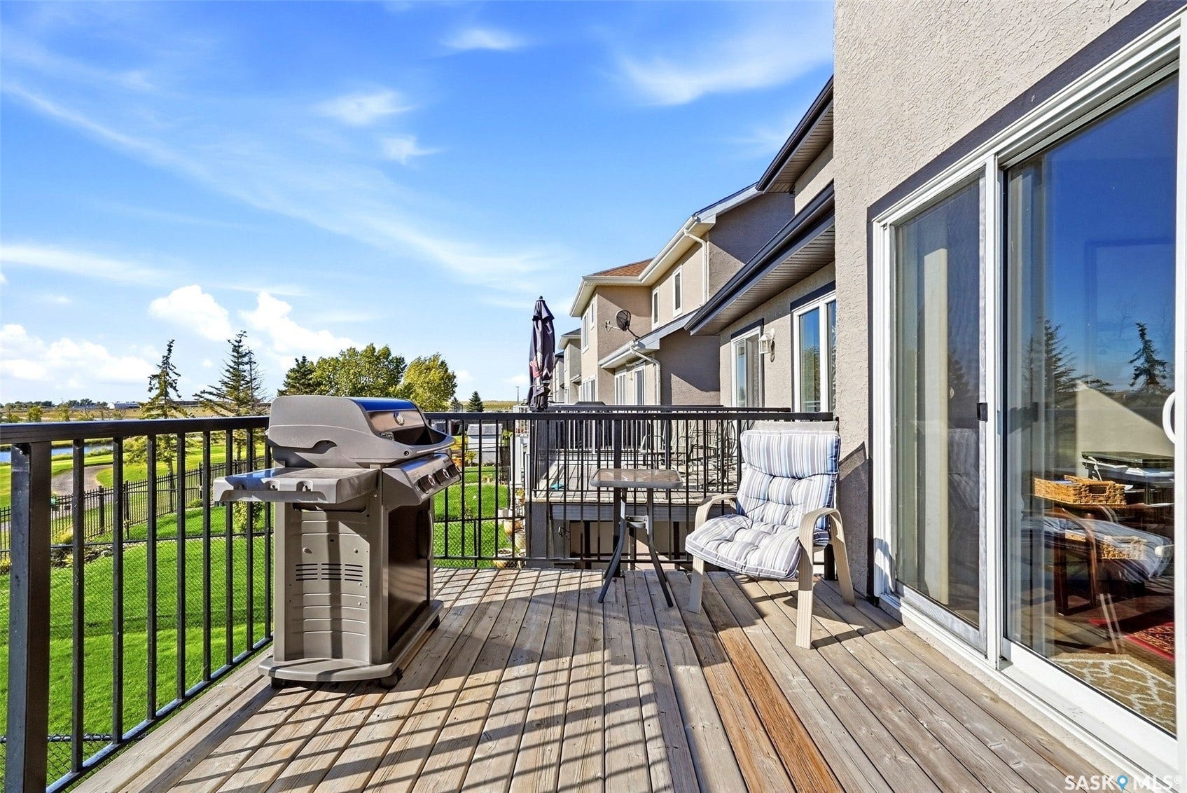 Expansive wood-finish deck with black metal railings and a sliding glass door