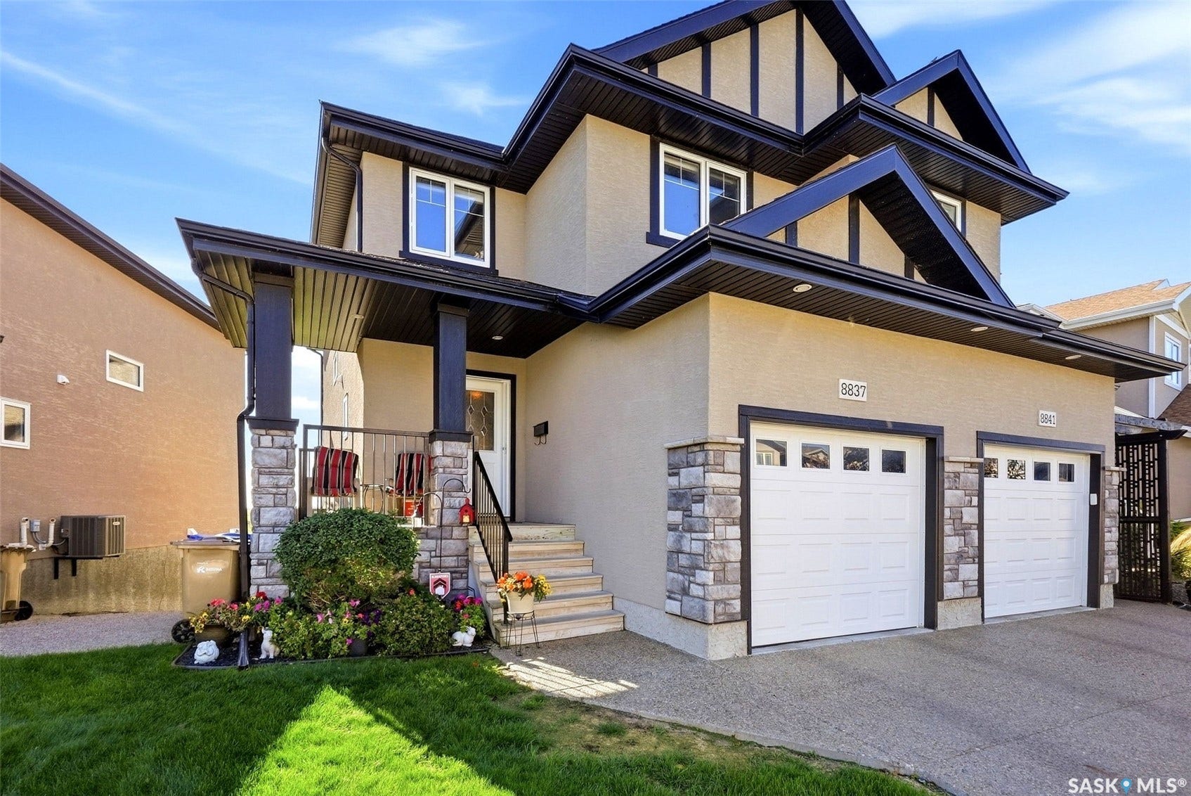 Stucco exterior with stone accents, covered front porch, dual garage doors, and a concrete driveway
