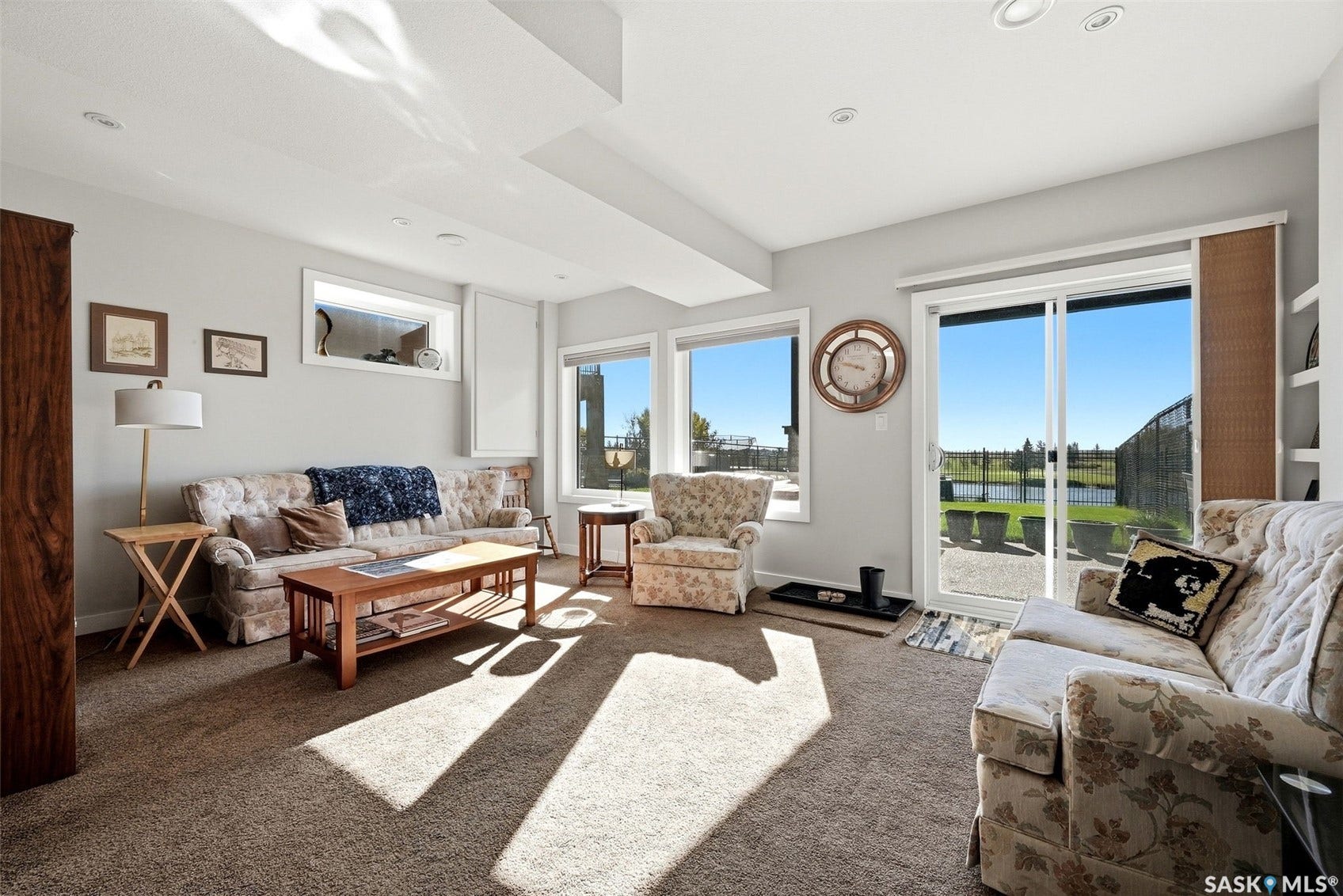 Recessed lighting, large sliding glass door, multiple windows, carpet flooring, and a built-in shelving unit