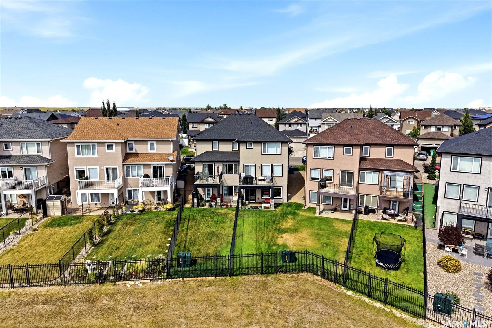 Two-story stucco exterior with multiple balconies, a lower-level patio, and a fenced backyard