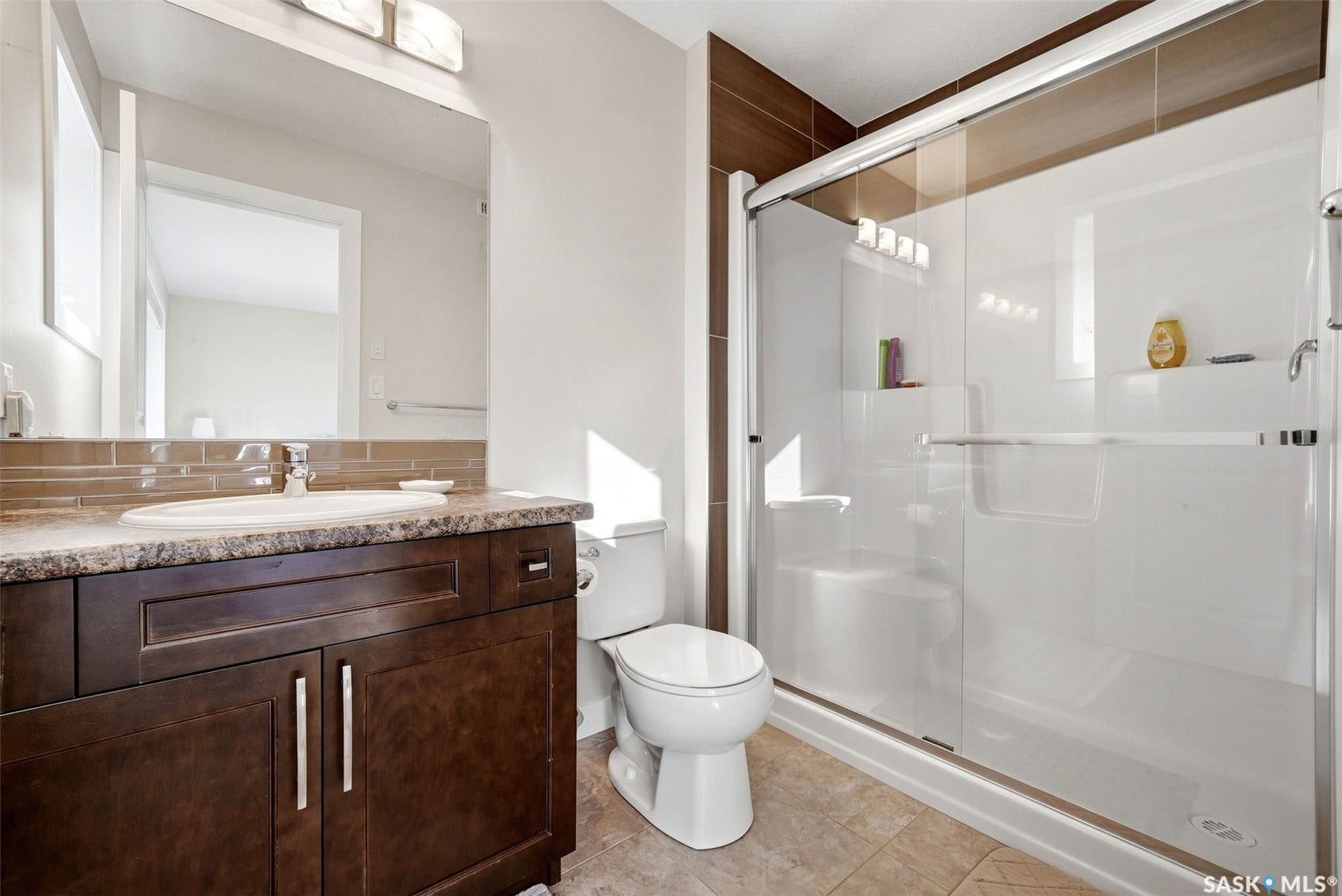 Dark wood-finish vanity with a built-in sink, granite-style countertop, and subway tile backsplash