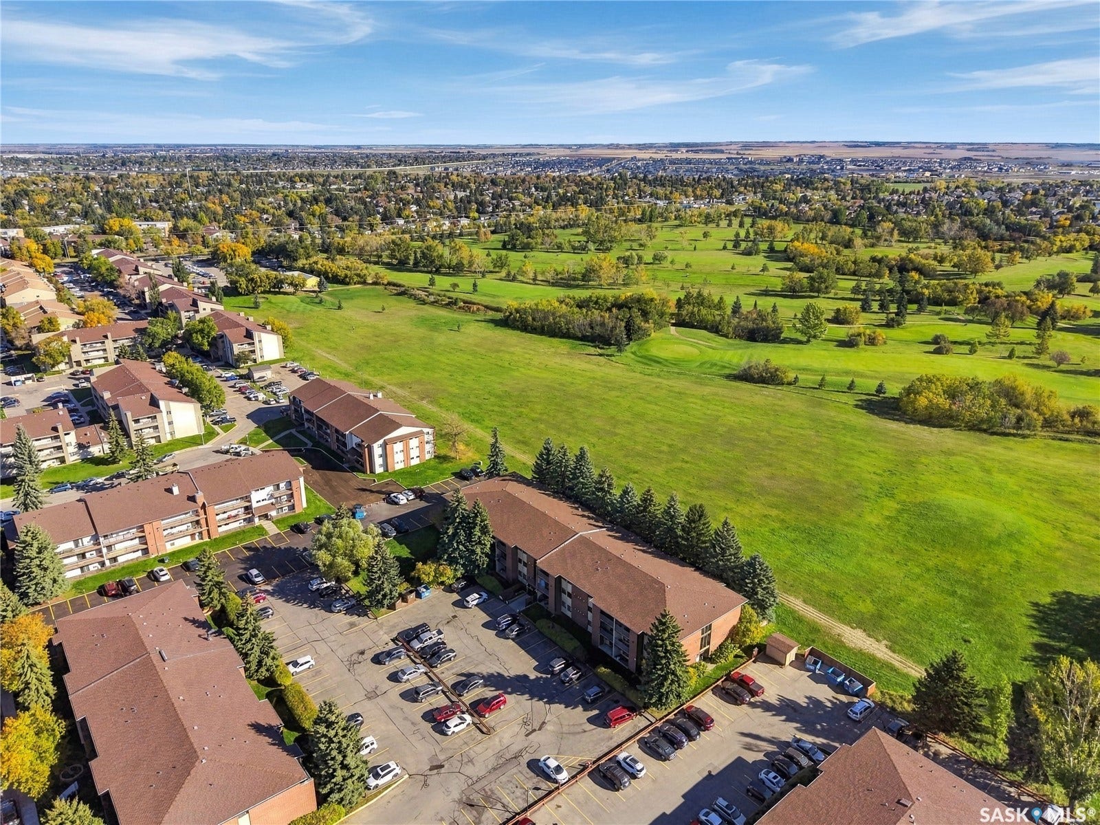 Expansive green spaces and mature trees surround multi-story buildings with brown brick exteriors and dark roofing
