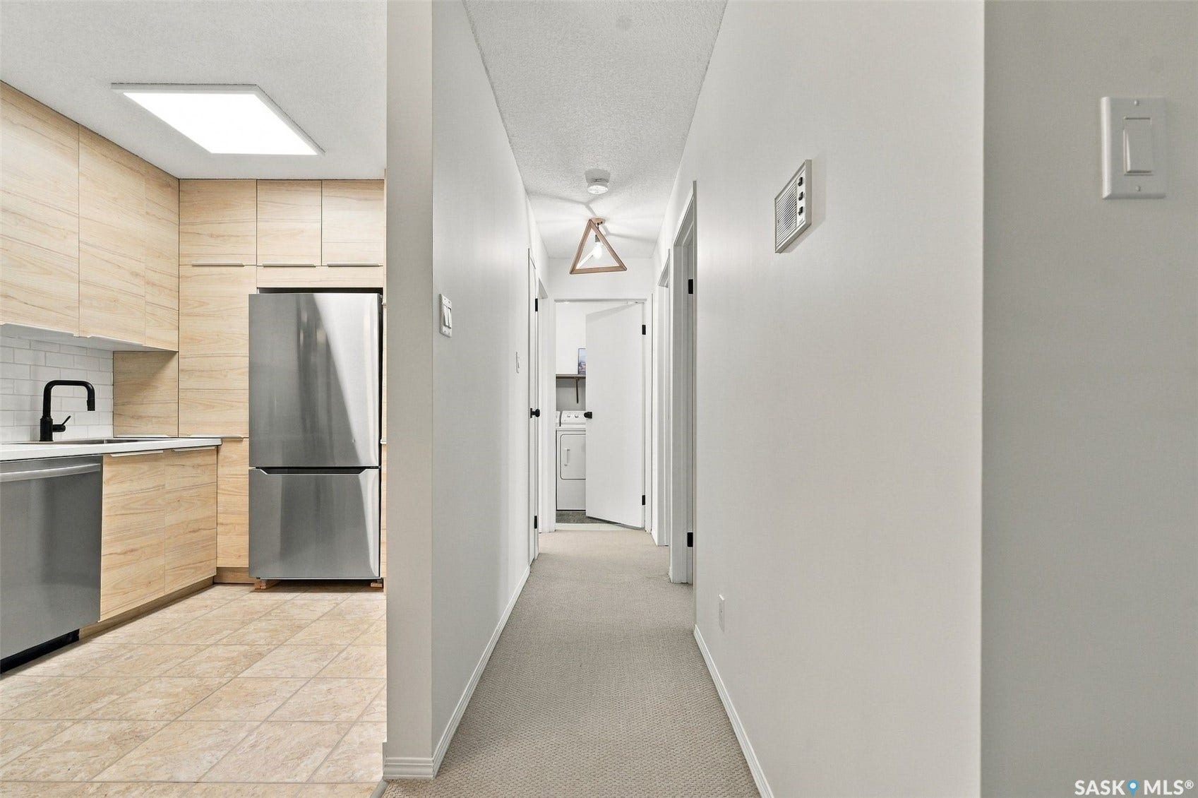 Kitchen featuring wood-finish cabinetry, stainless steel appliances, a matte black faucet, white subway tile backsplash, and ceramic floor tiling