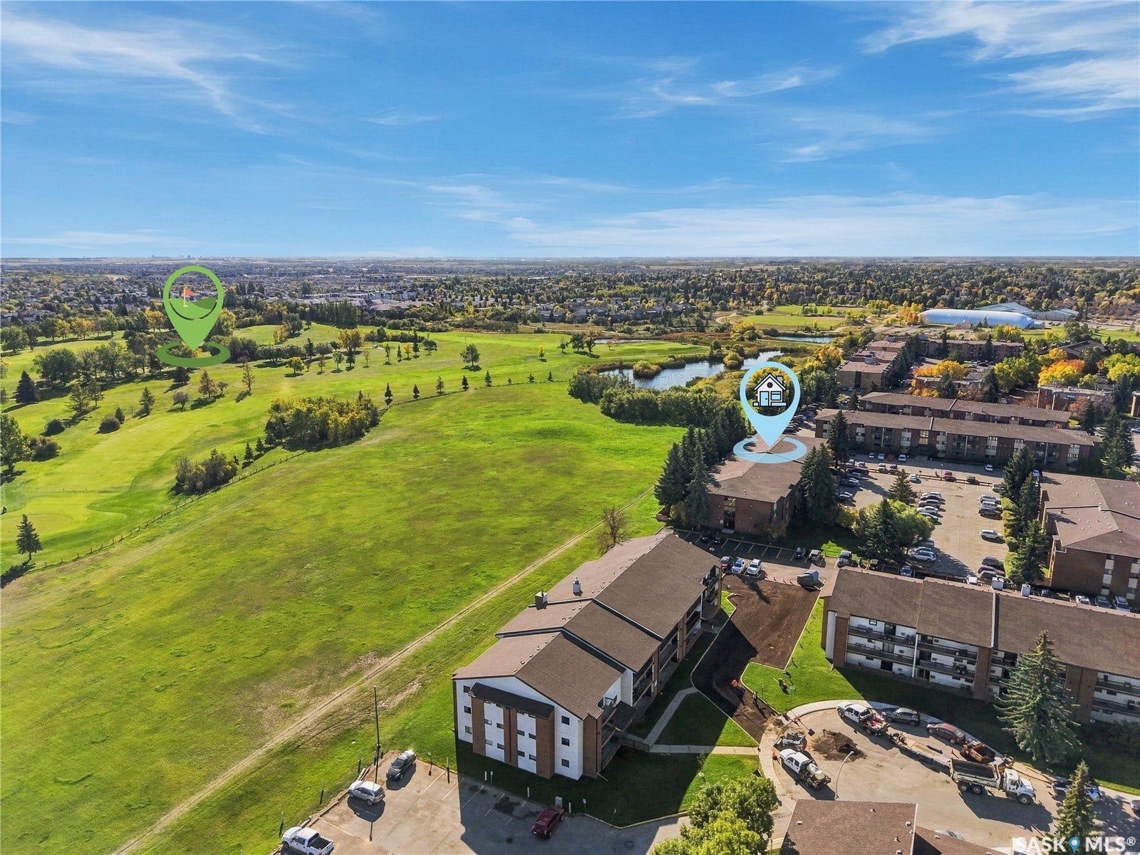 Expansive green spaces and mature trees surround the property, with a water feature visible in the distance