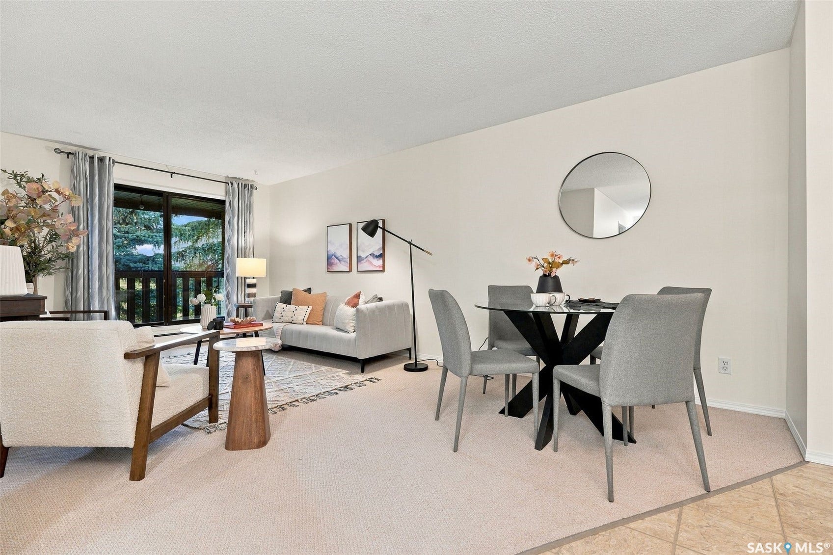 Expansive living area with neutral carpeting, sliding glass door to a balcony, and abundant natural light