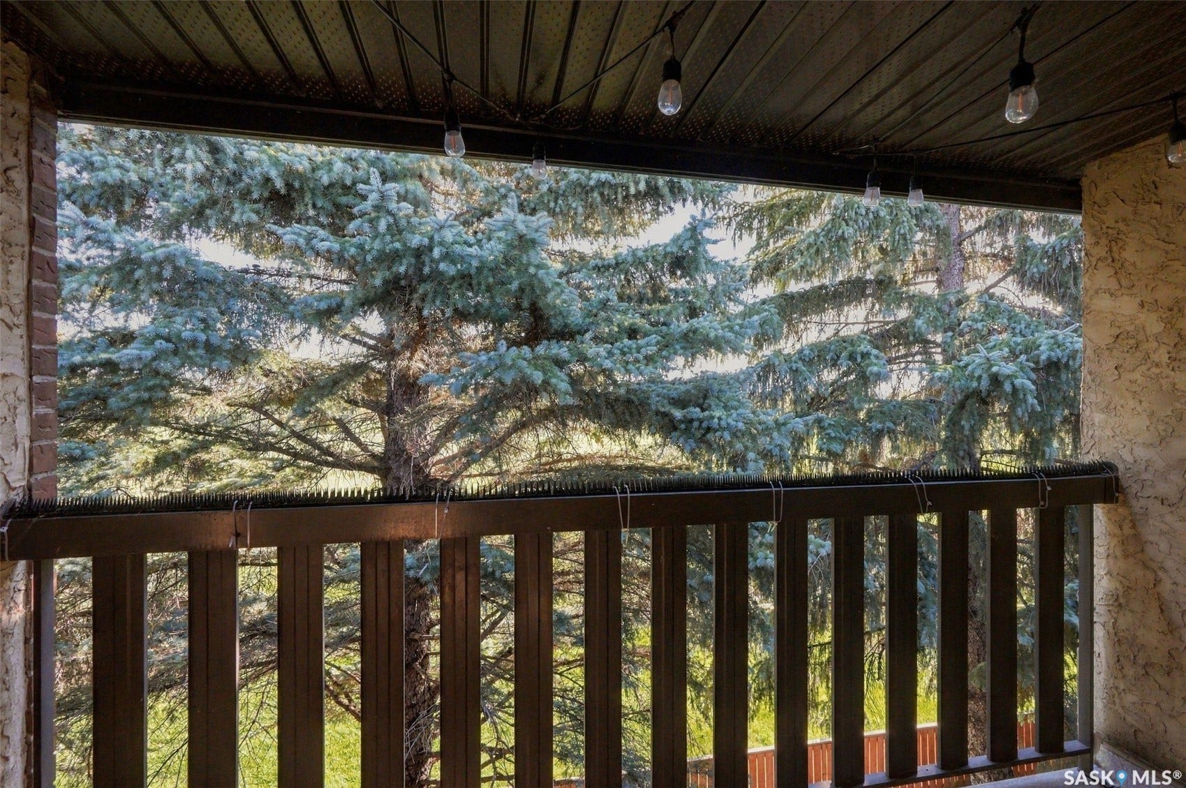 Balcony featuring a wooden railing and textured exterior wall