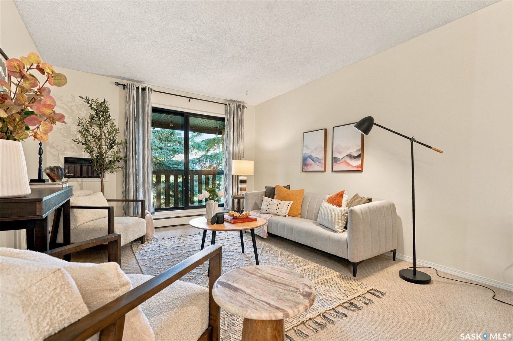 Living area featuring a large window, a balcony with a black railing, and neutral wall tones