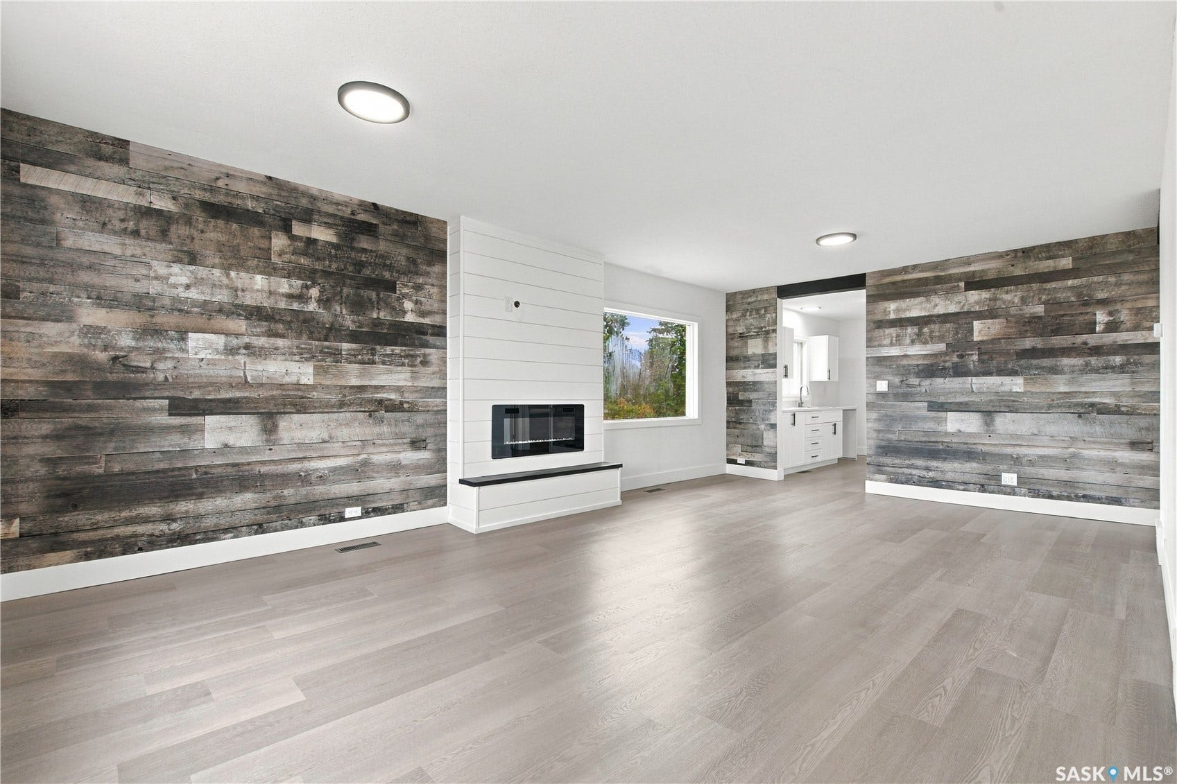 Light wood-finish flooring complemented by a shiplap fireplace surround
