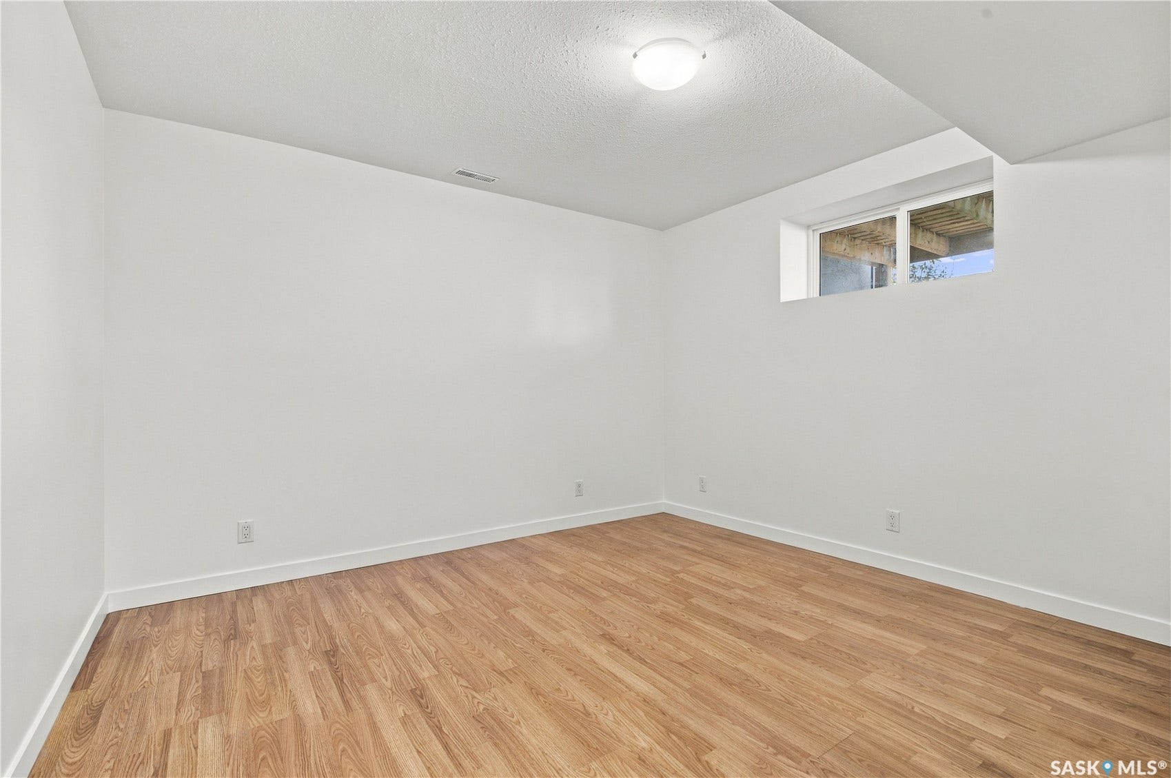 Wood-finish flooring, white walls, white trim, recessed window, and flush-mount ceiling light