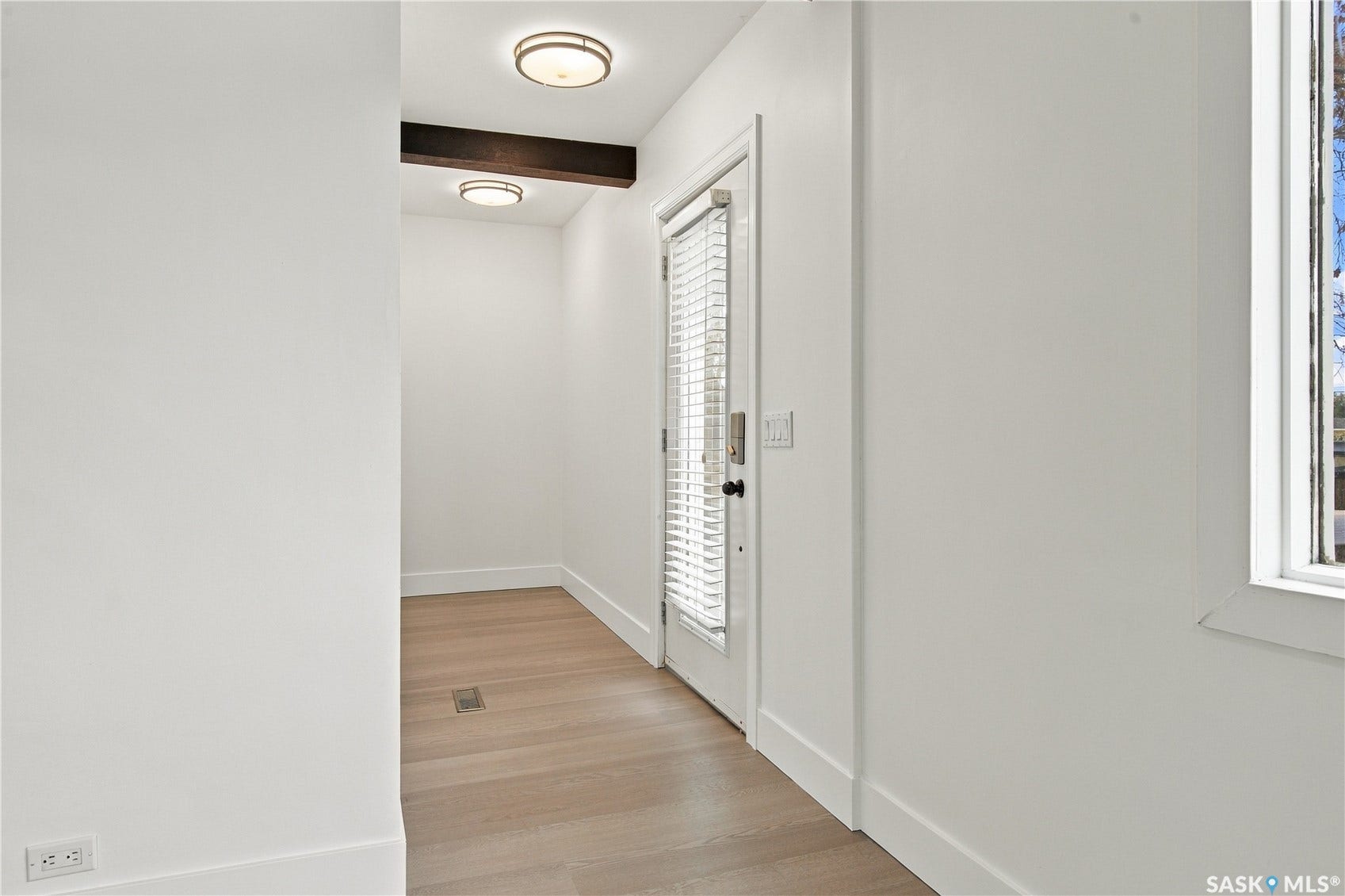 Wood-finish flooring, white walls, and a prominent wood beam